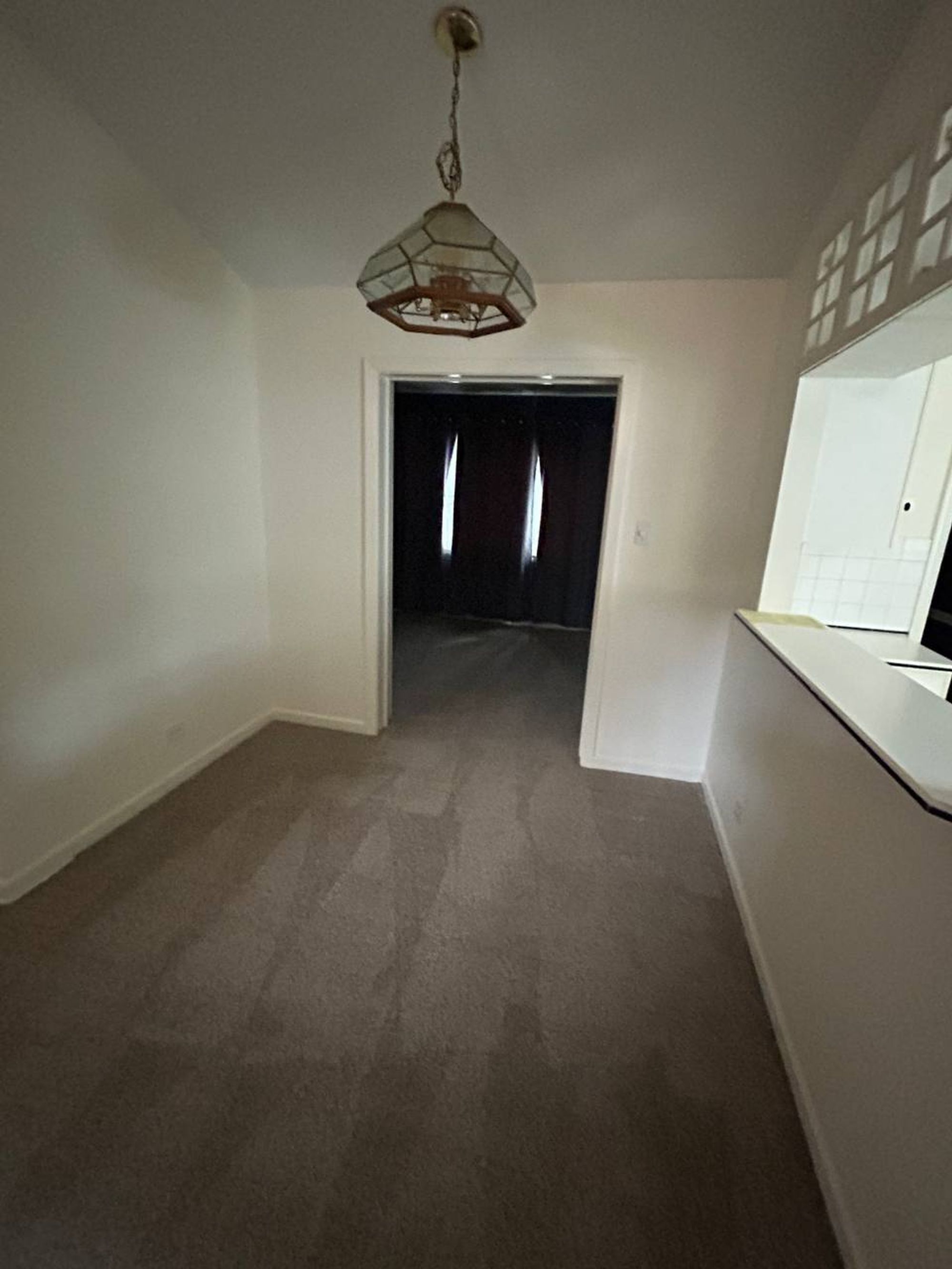 Empty dining area with carpet, hanging light and pass through counter