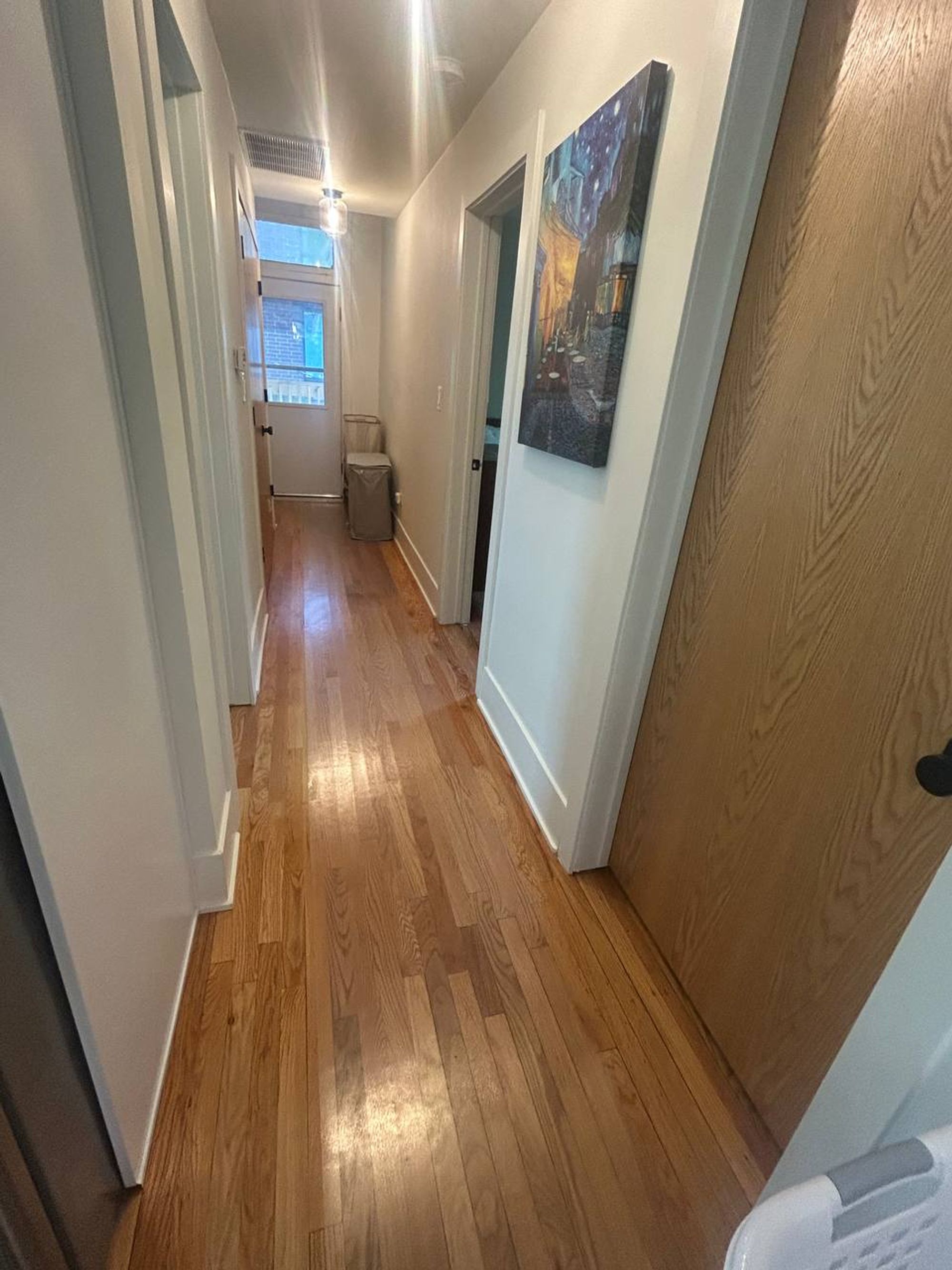 Long hallway with shiny oak floor and white doors