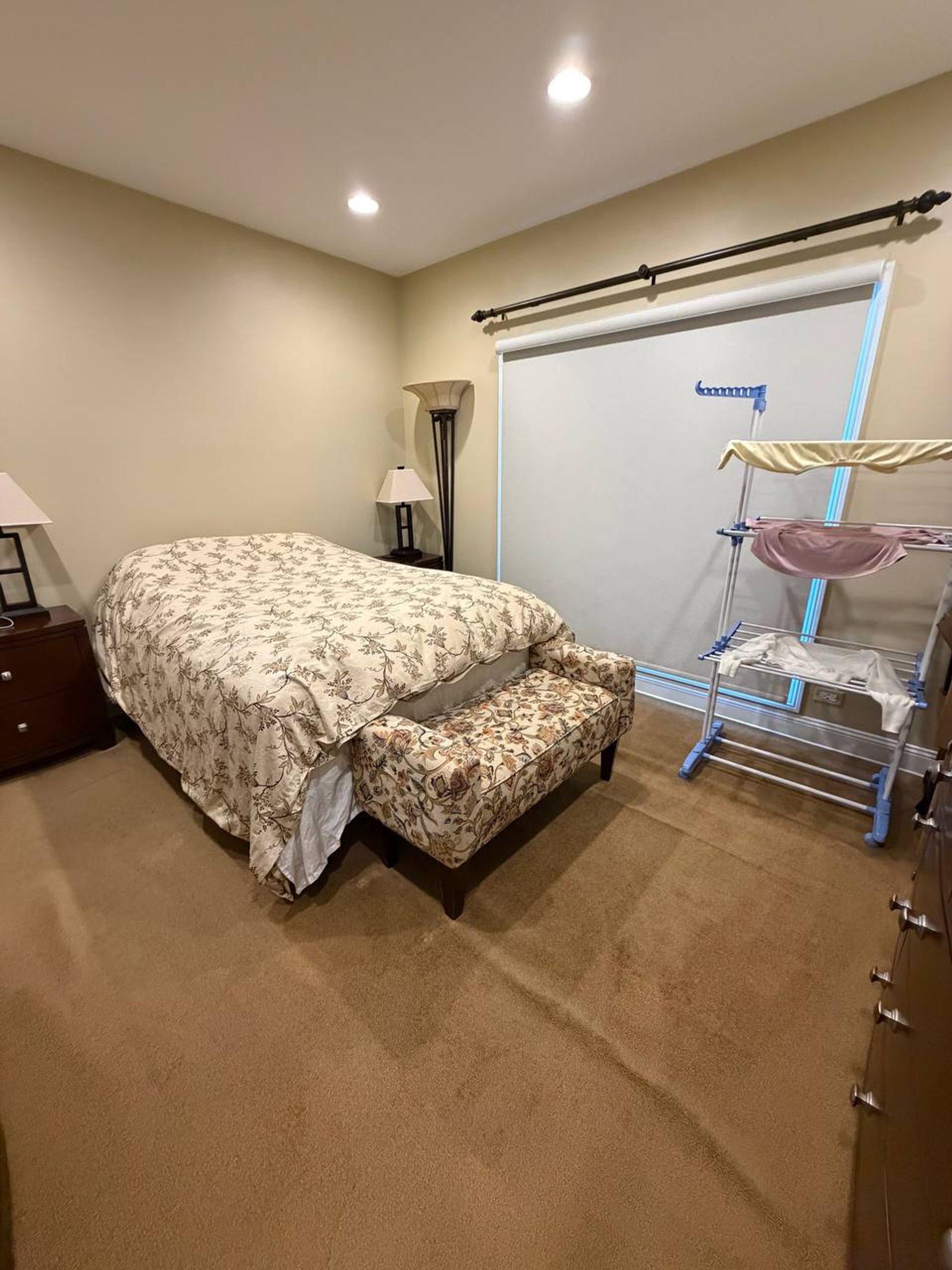 Guest bedroom with made bed, upholstered bench and vacuumed carpet