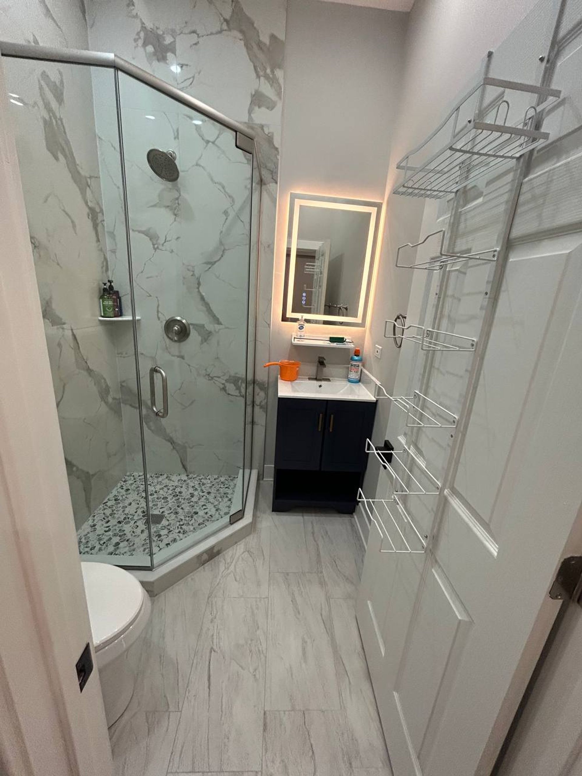 Bathroom with glass shower, lighted mirror and navy vanity