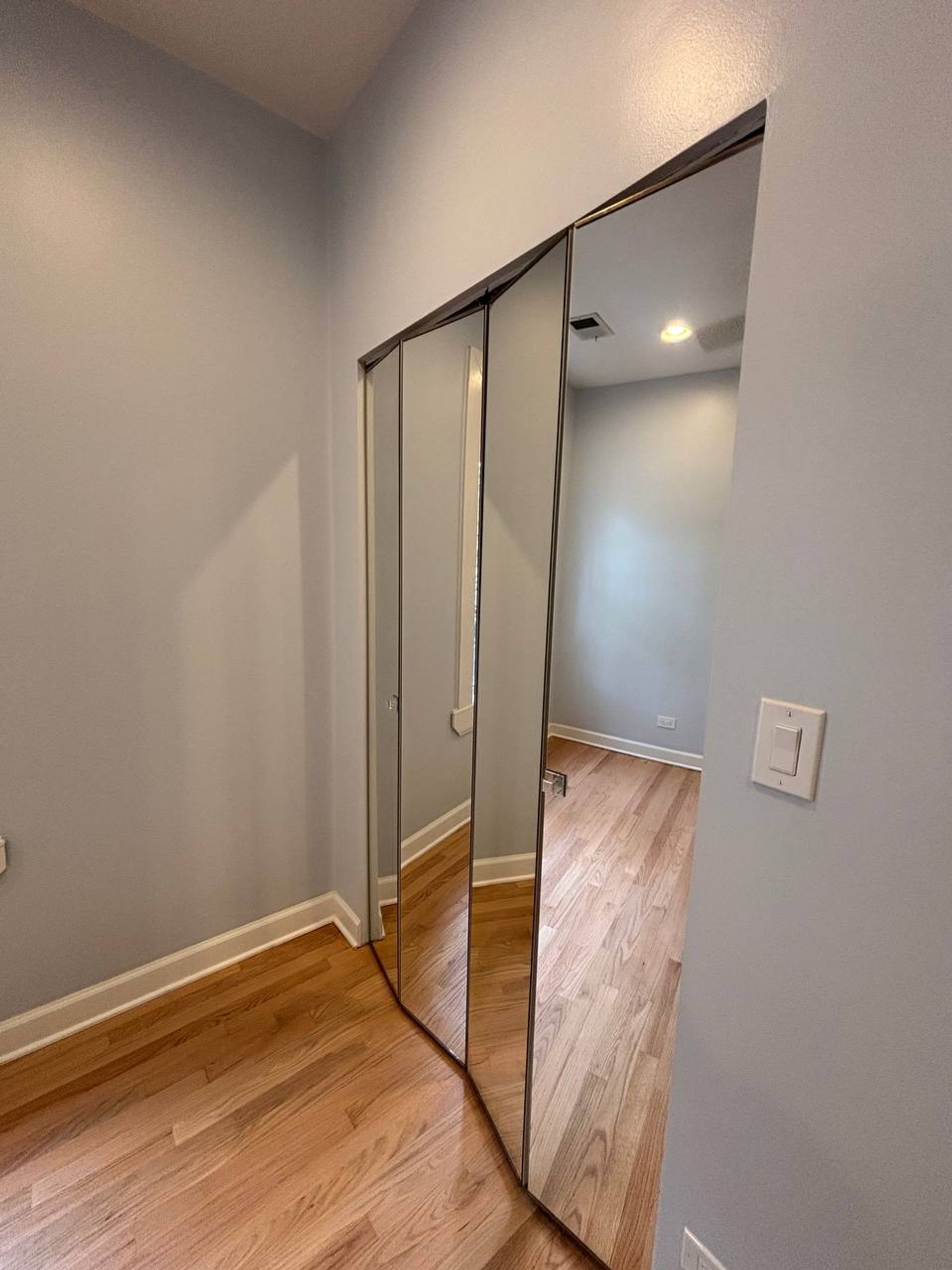 Hallway with tall mirrored closet doors and light oak floor