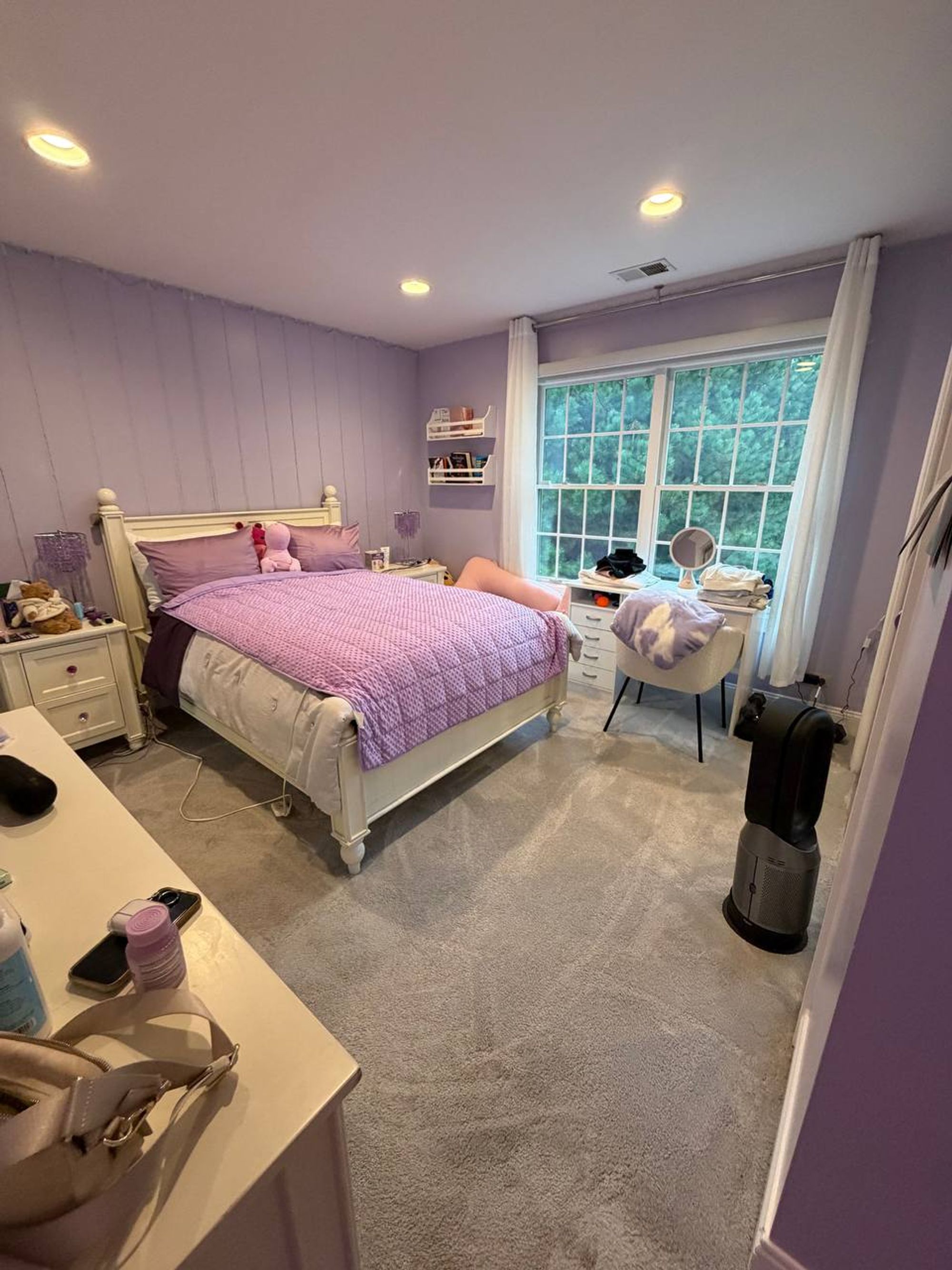 Lilac bedroom with made bed, white furniture and vacuumed carpet