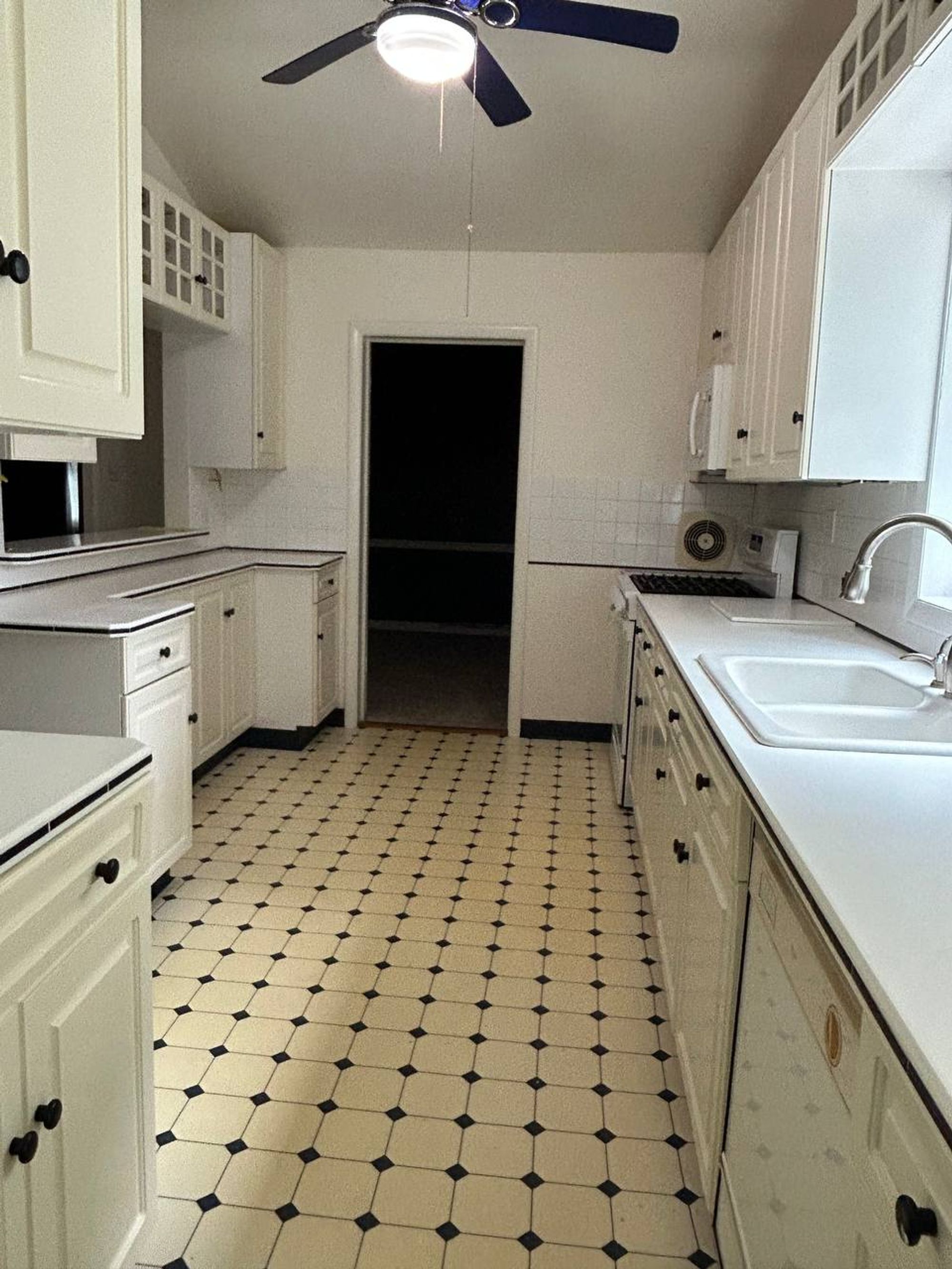 White galley kitchen with wiped counters and checked tile floor