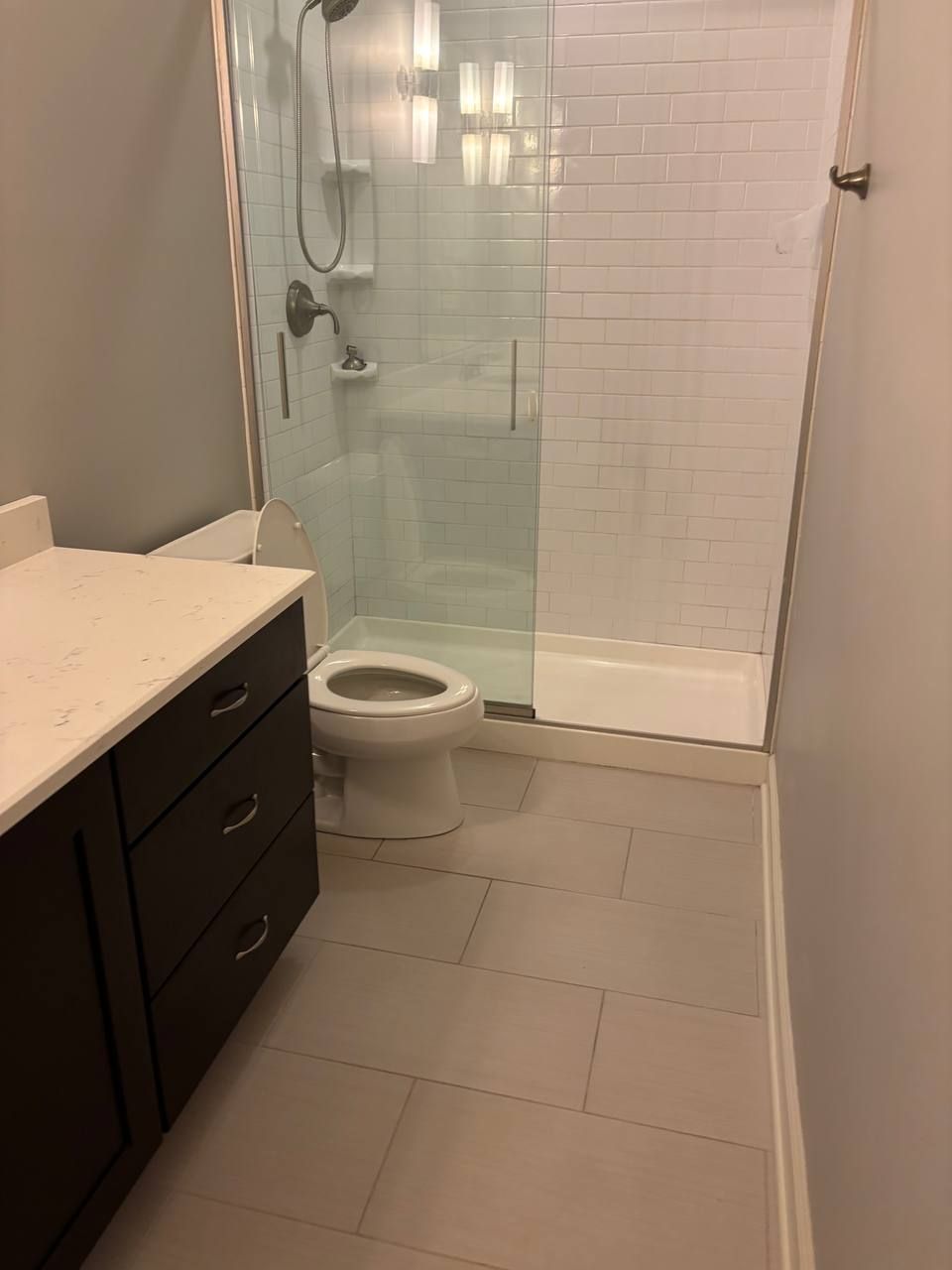 Bathroom with glass shower, dark vanity and light gray floor tile
