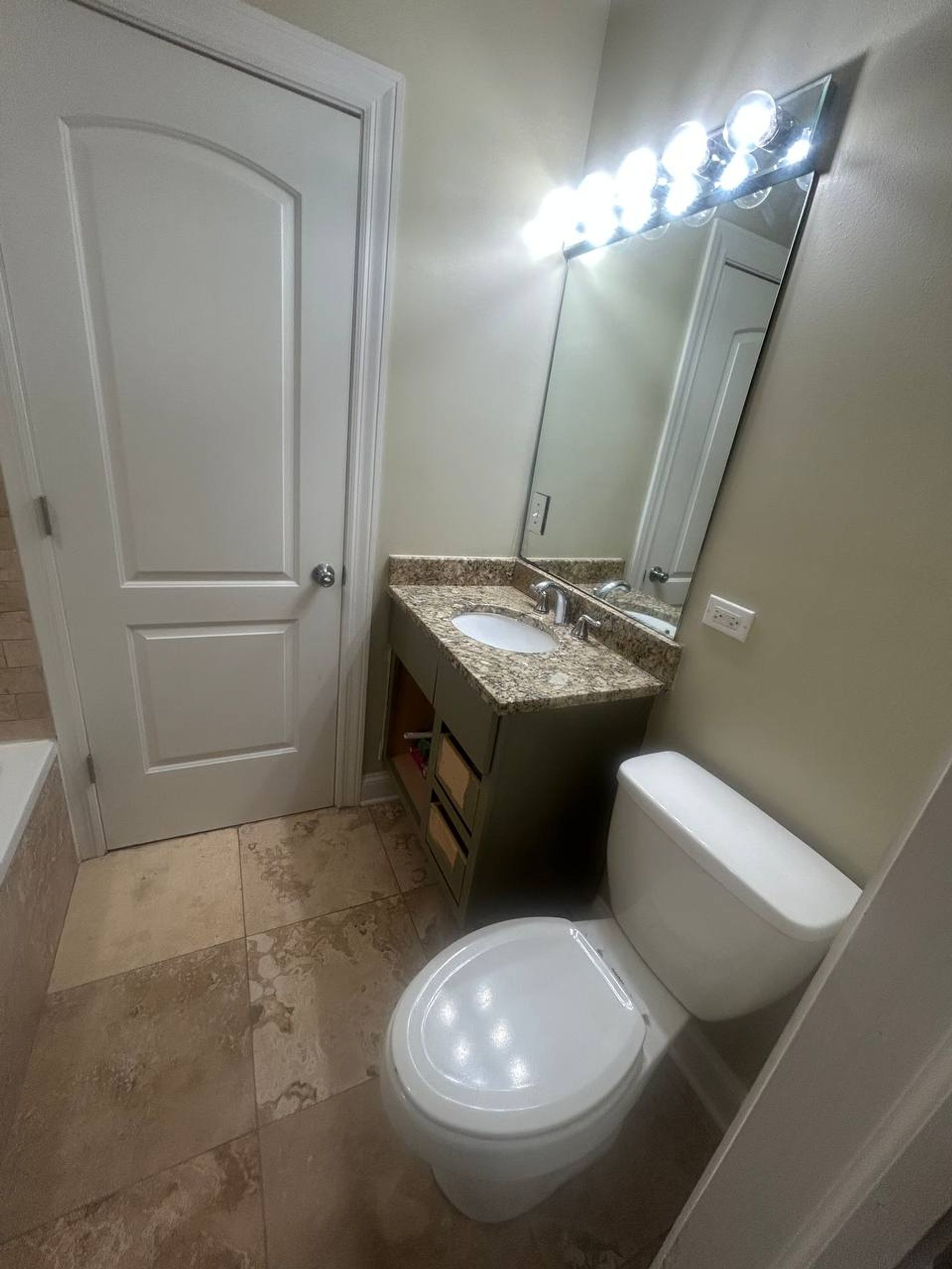 Bathroom with granite vanity, bright light bar and white toilet