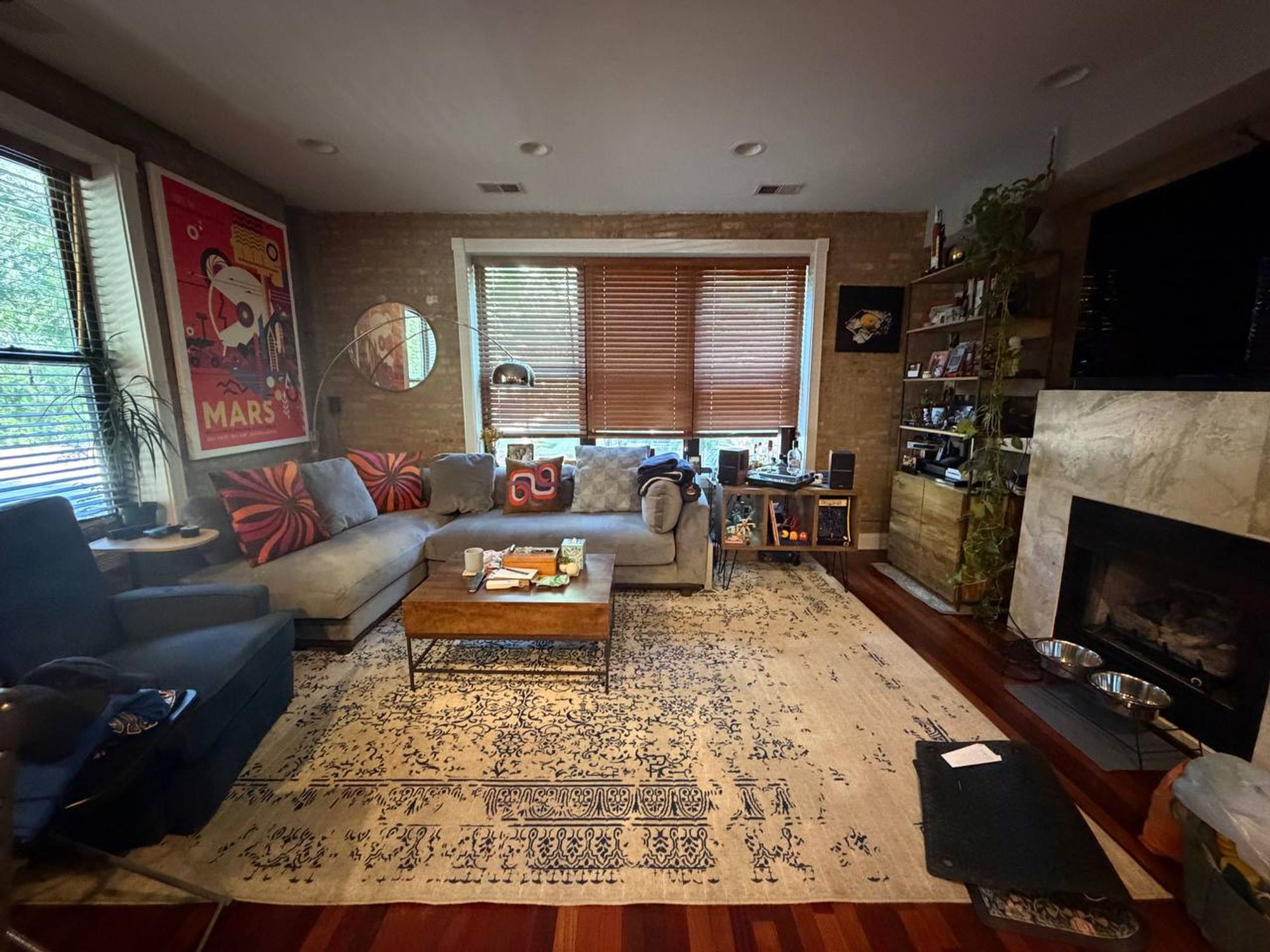 Living room with sectional sofa, area rug, brick wall and fireplace