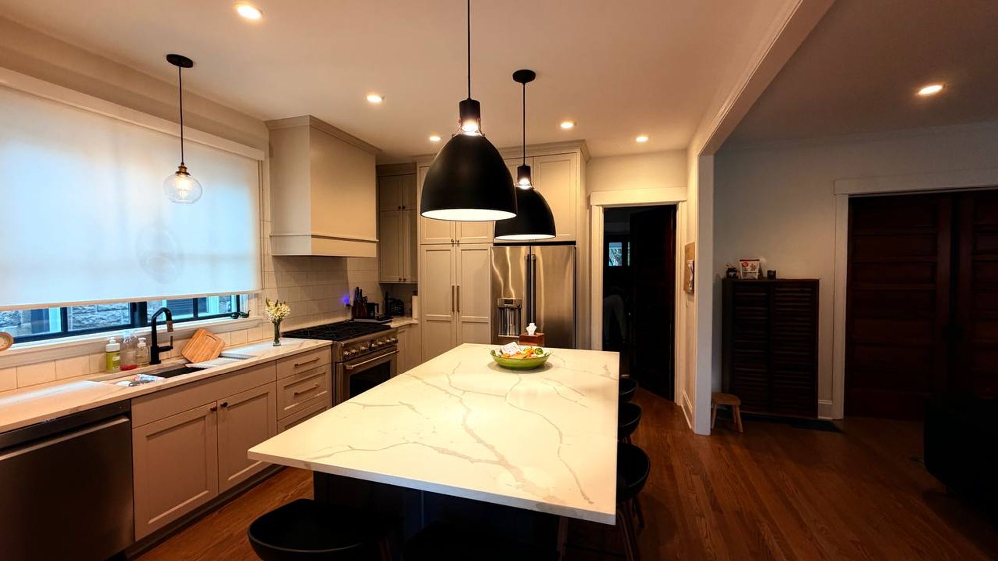 Kitchen with white stone island, black pendants and steel range