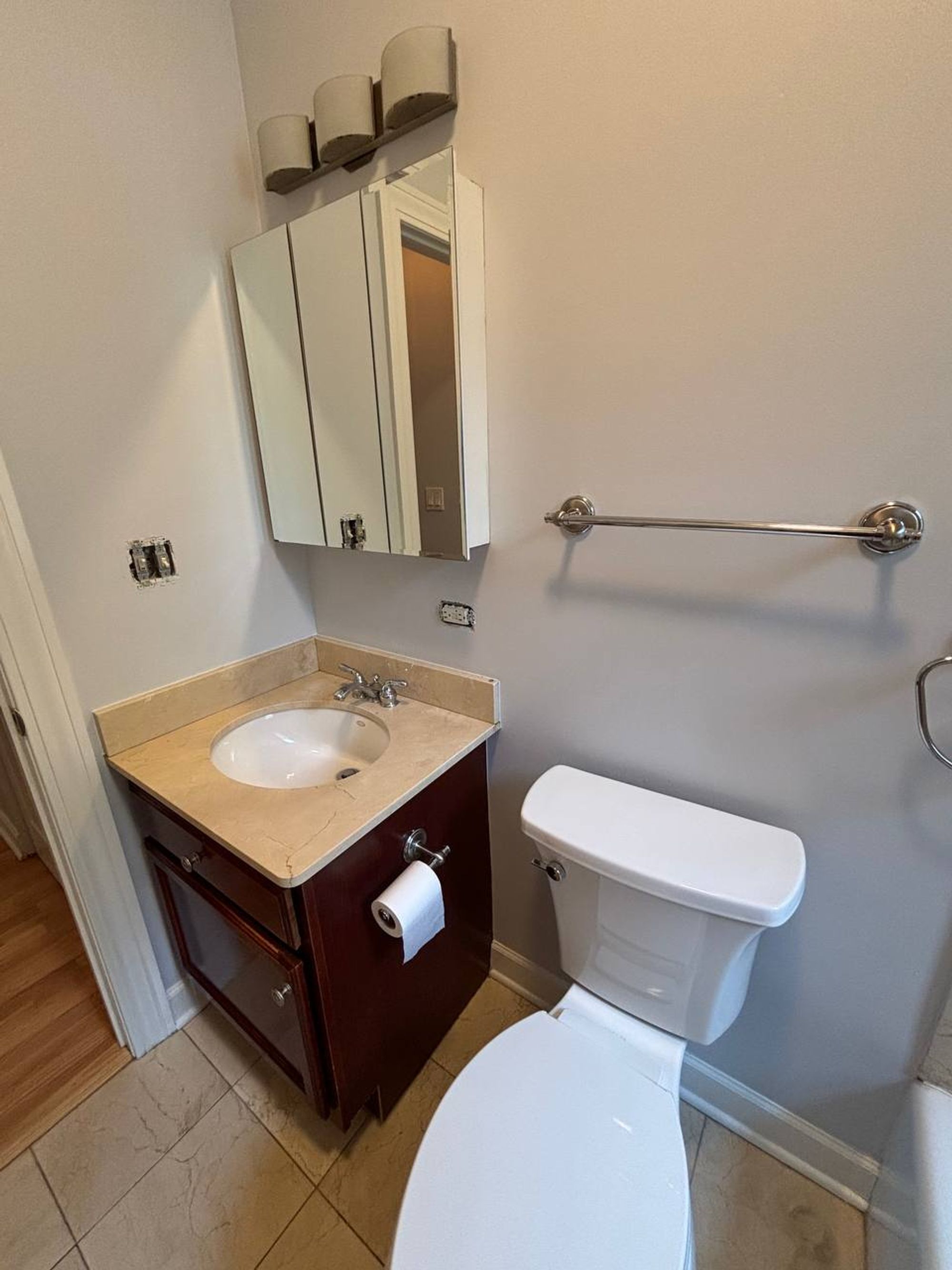 Half bath with dark wood vanity, medicine cabinet and white toilet