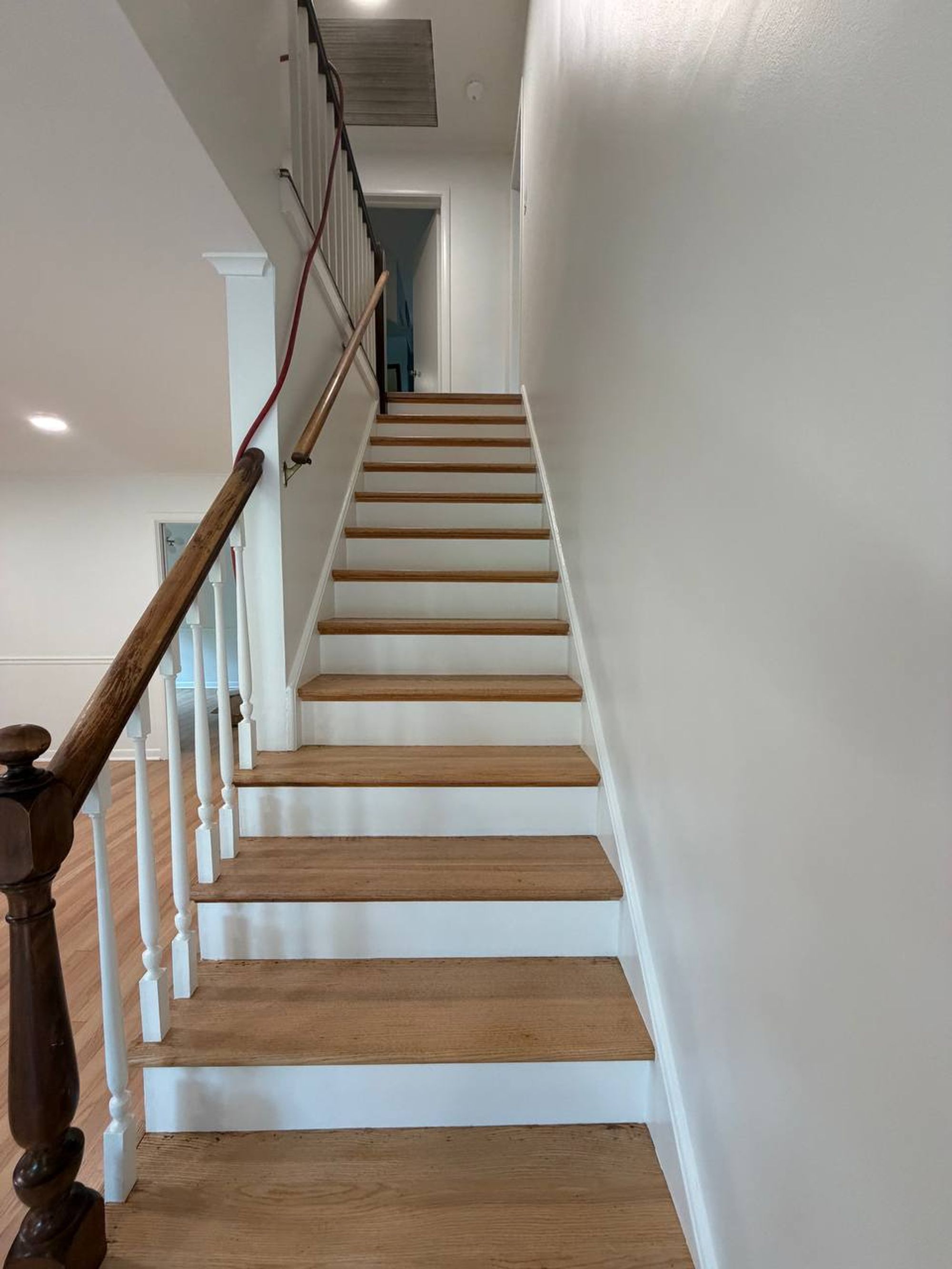 Wooden staircase with white risers and a dark wood handrail