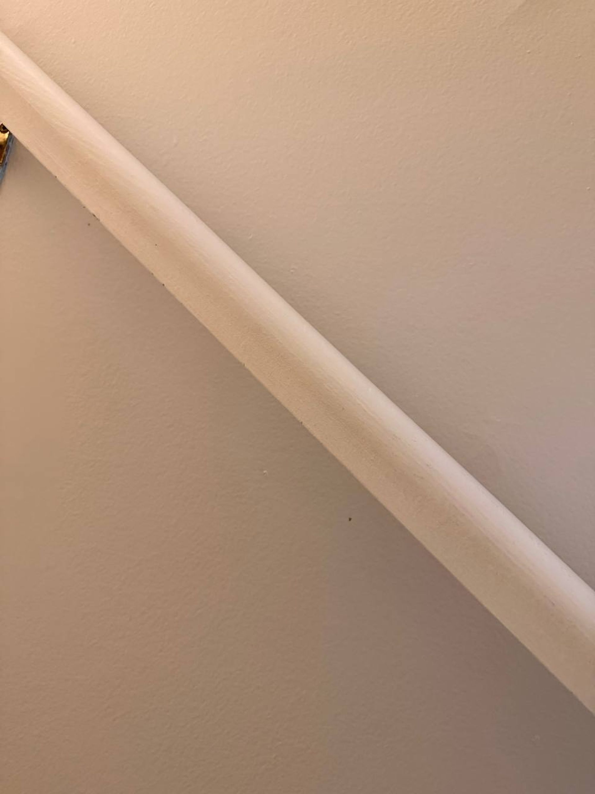 Clean painted stair handrail along a beige wall