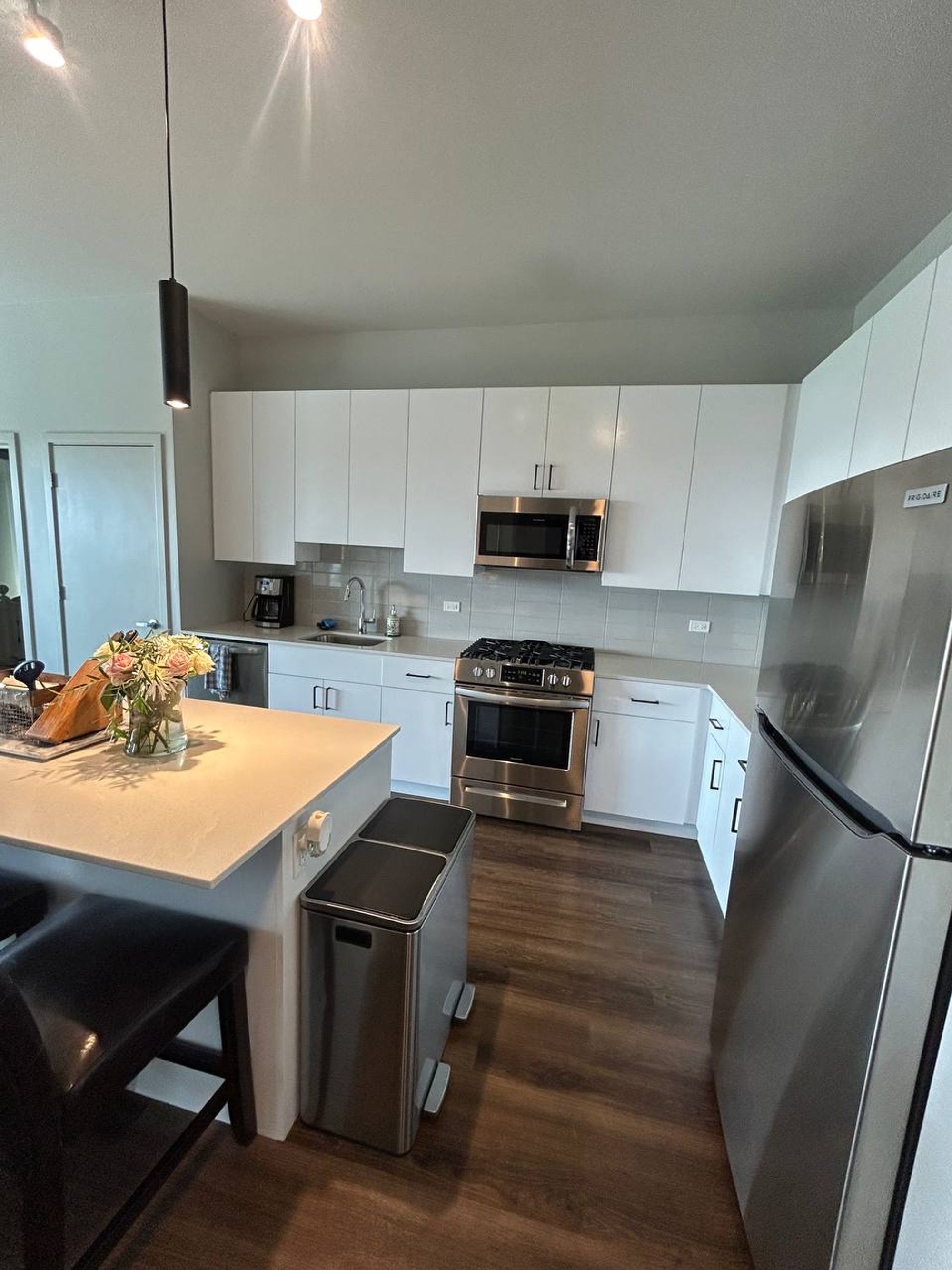 White kitchen with island, stainless range and stainless fridge