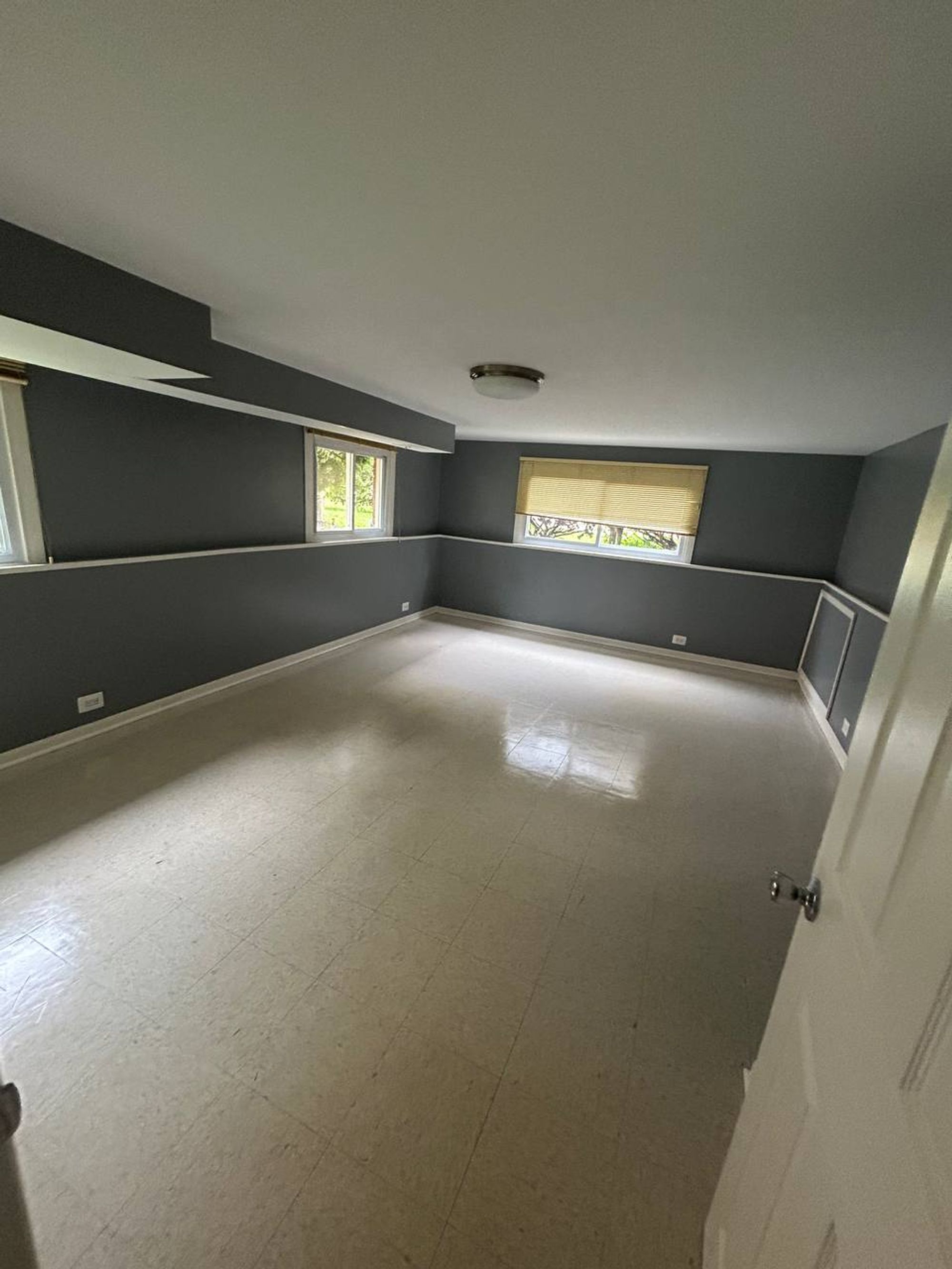 Empty lower level room with gray walls and shiny tile floor