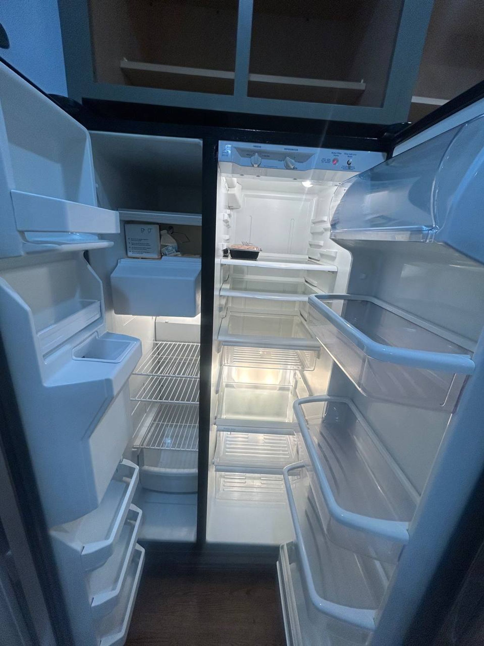 Empty side by side fridge with clean glass shelves and bins