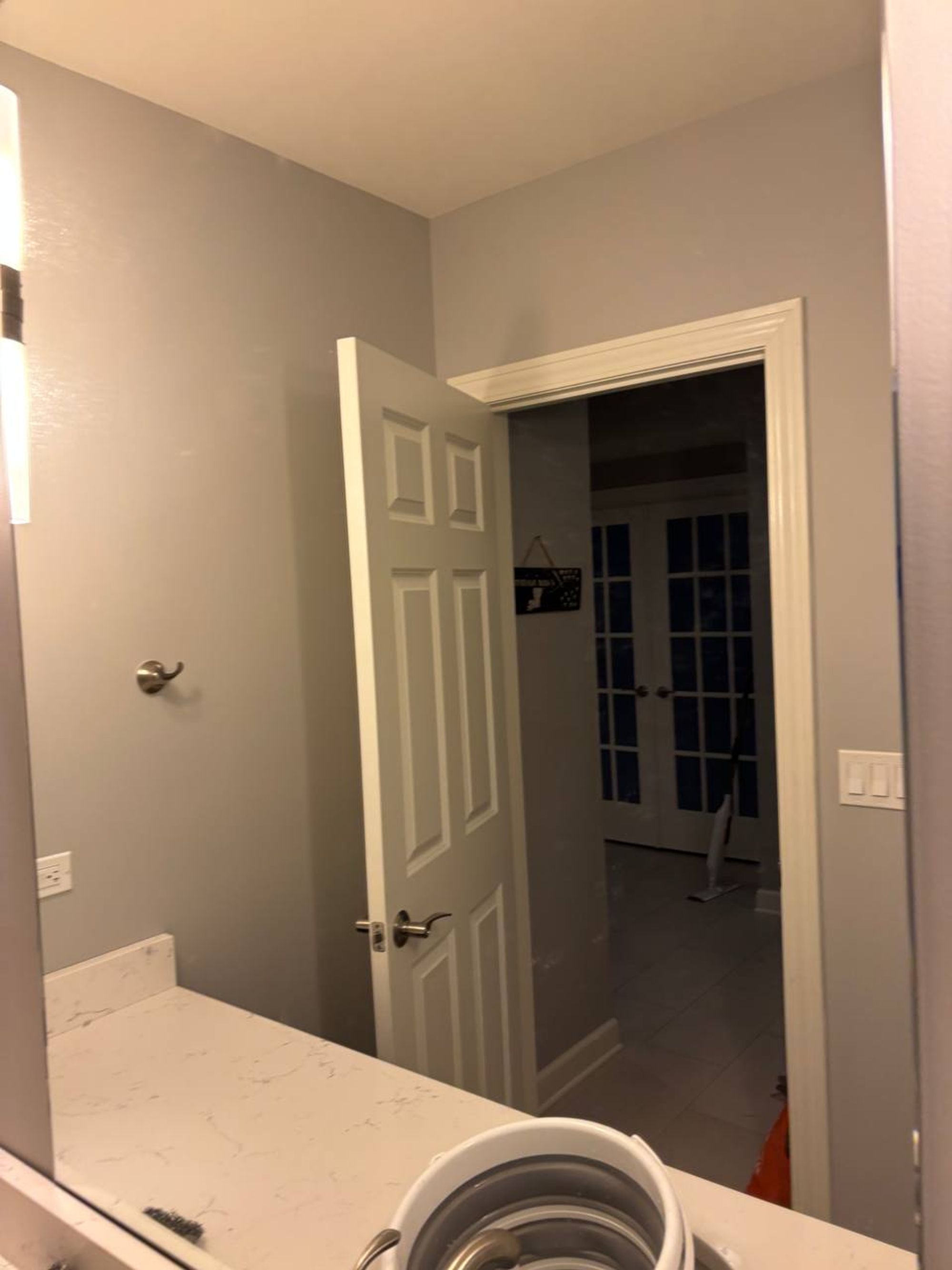 Clean bathroom mirror reflecting an open white panel door