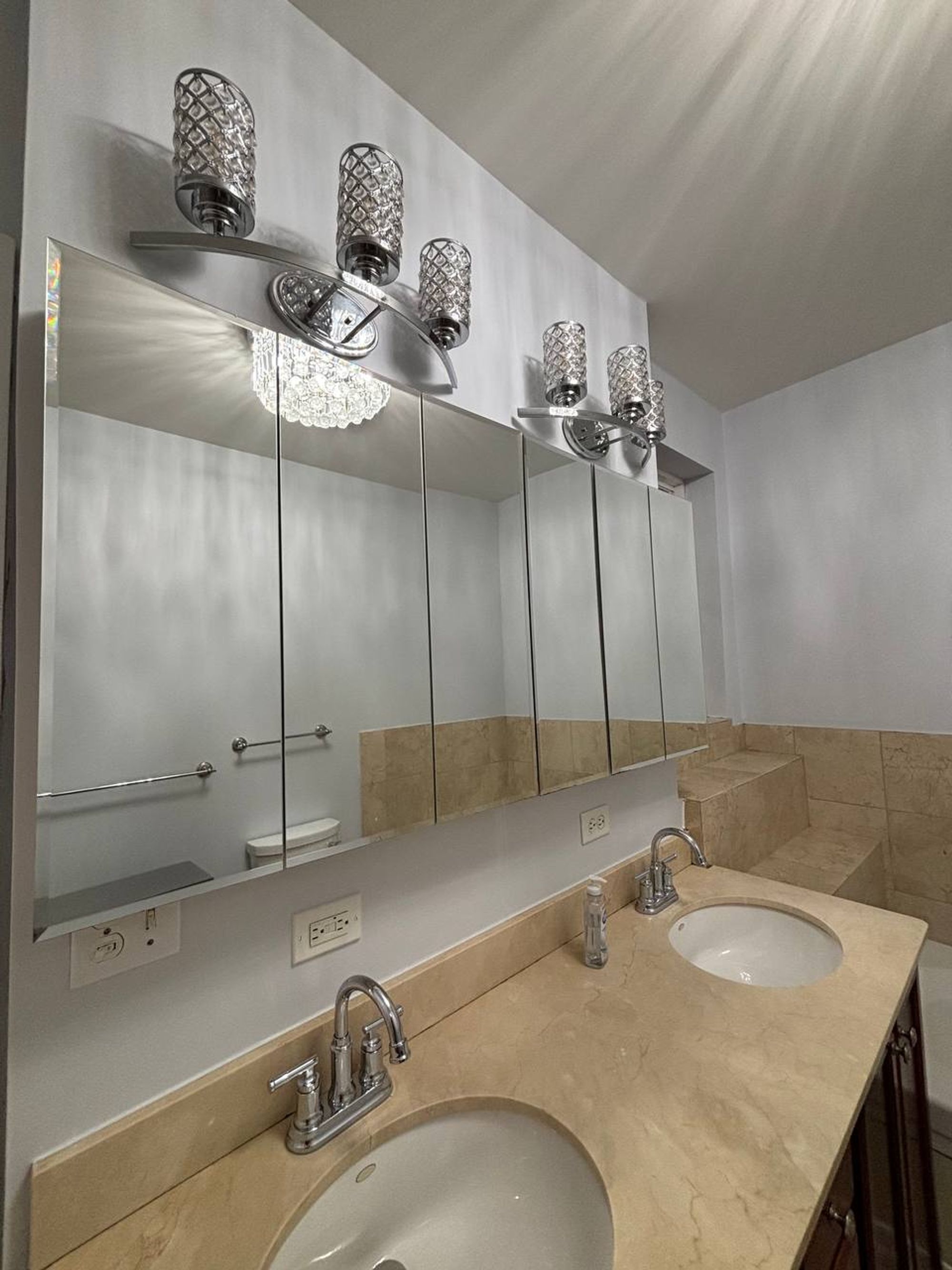 Double vanity with marble top, wide mirror and crystal lights