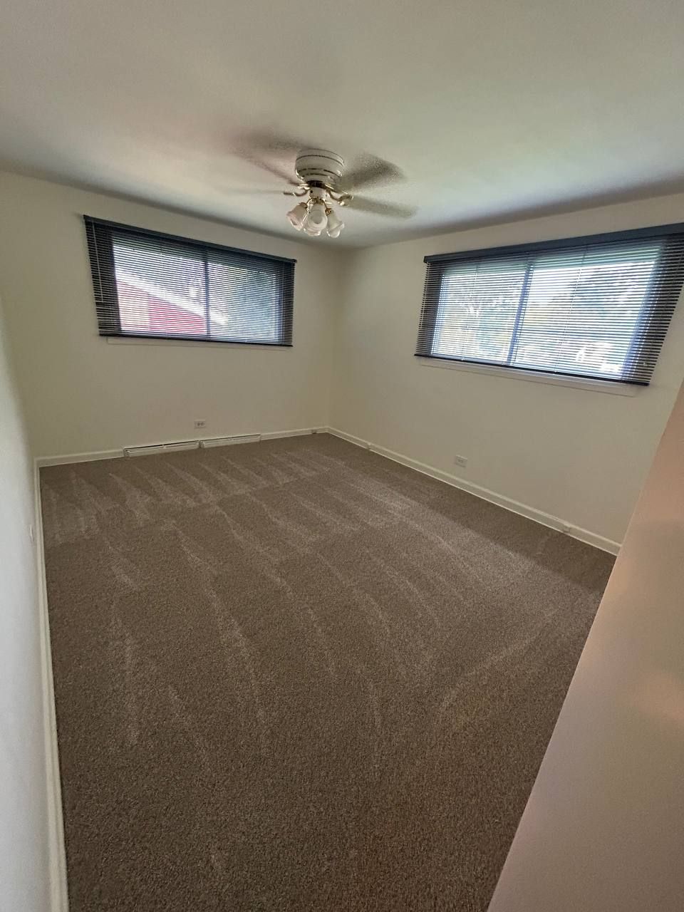 Empty bedroom with two blind covered windows and a ceiling fan