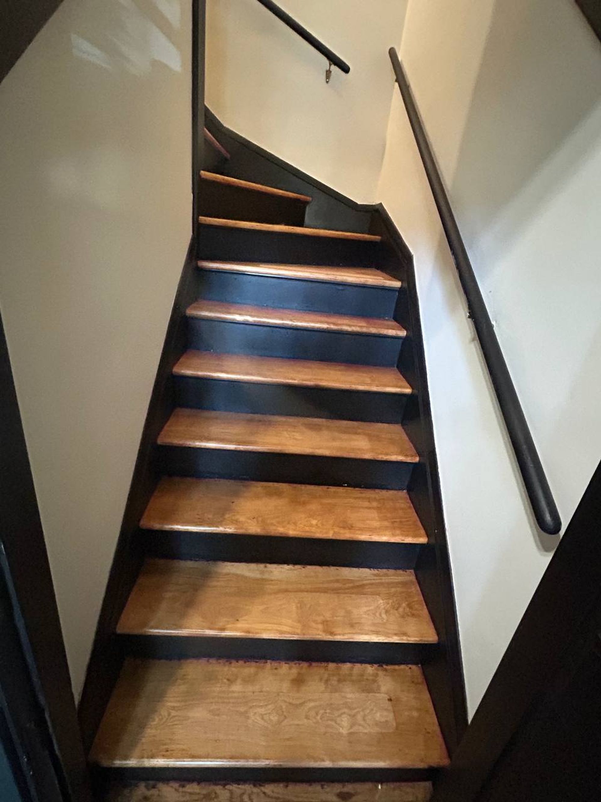 Wood stair treads with black risers and handrail