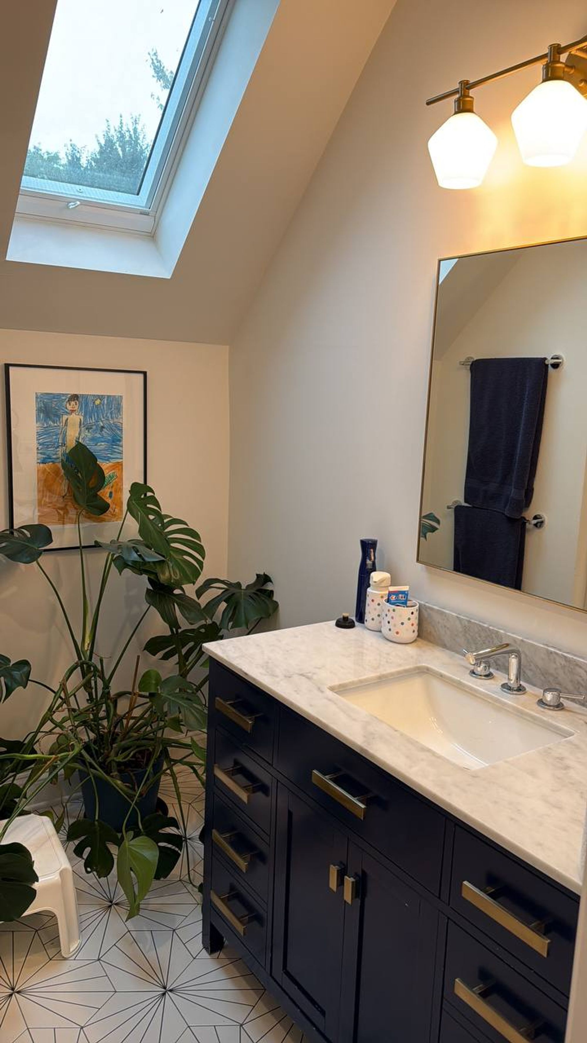 Bathroom with navy vanity, marble top and skylight above