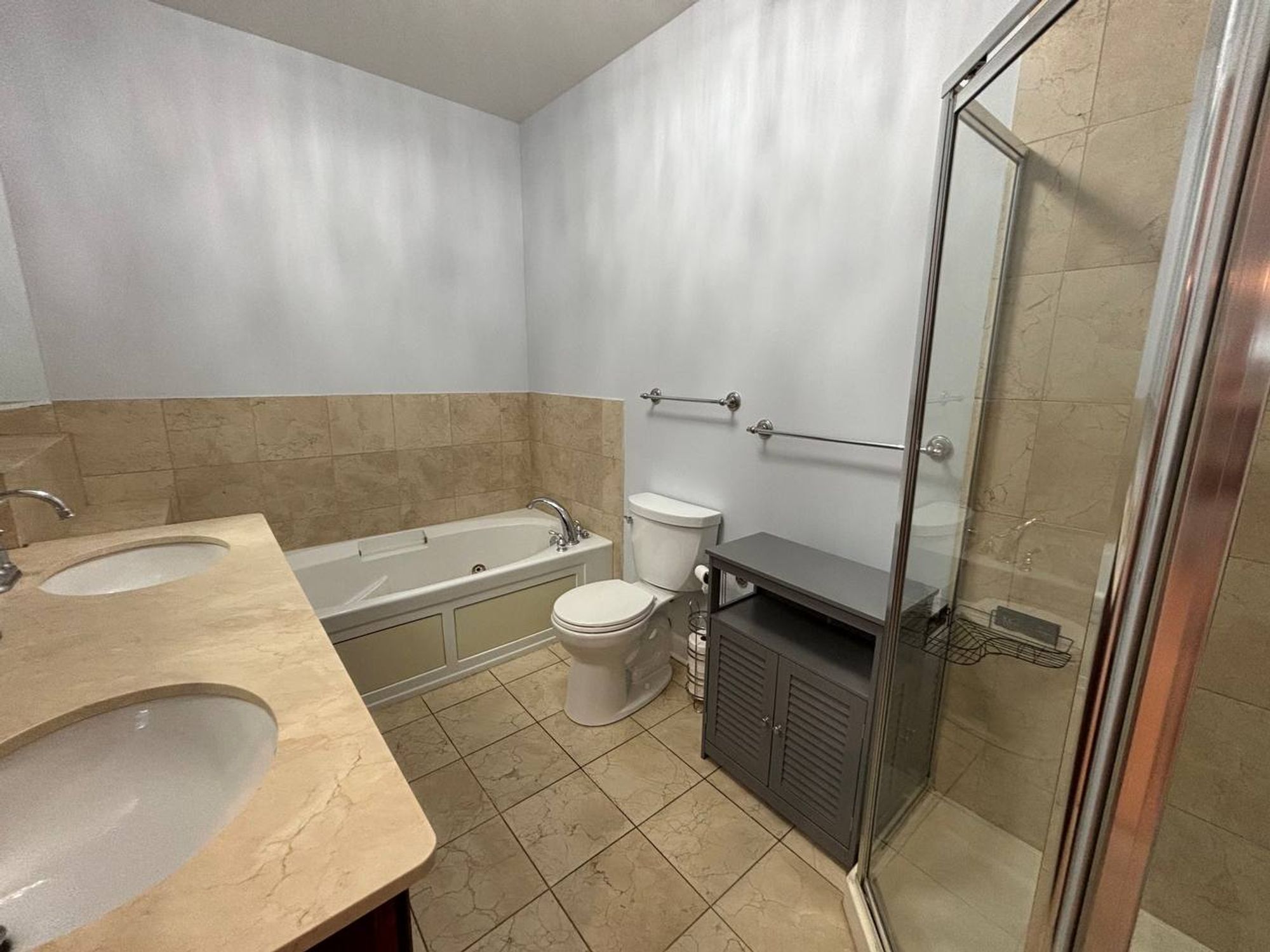 Clean bathroom with jetted tub, toilet and glass corner shower