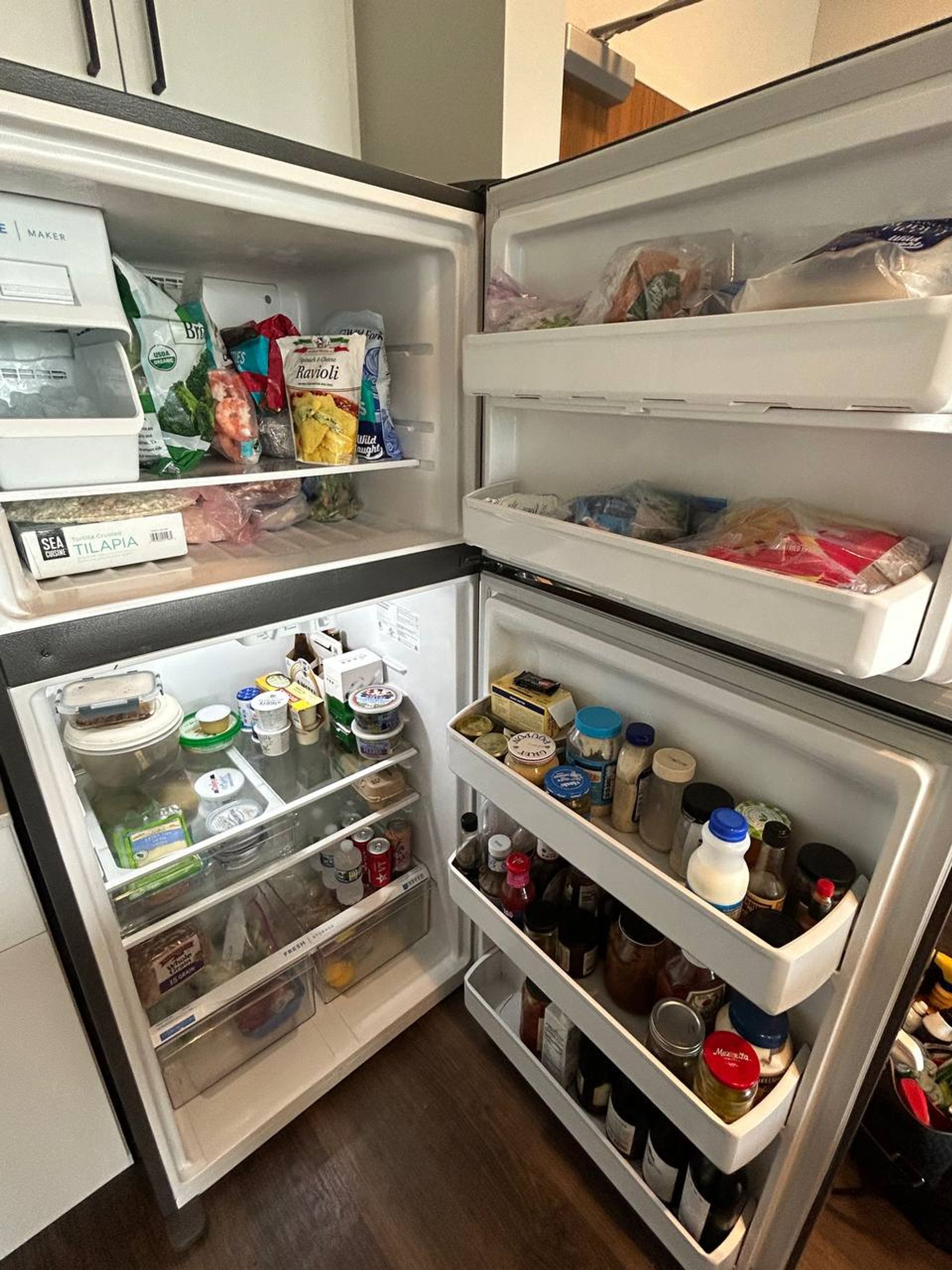 Top freezer fridge with wiped shelves and neatly stocked door bins