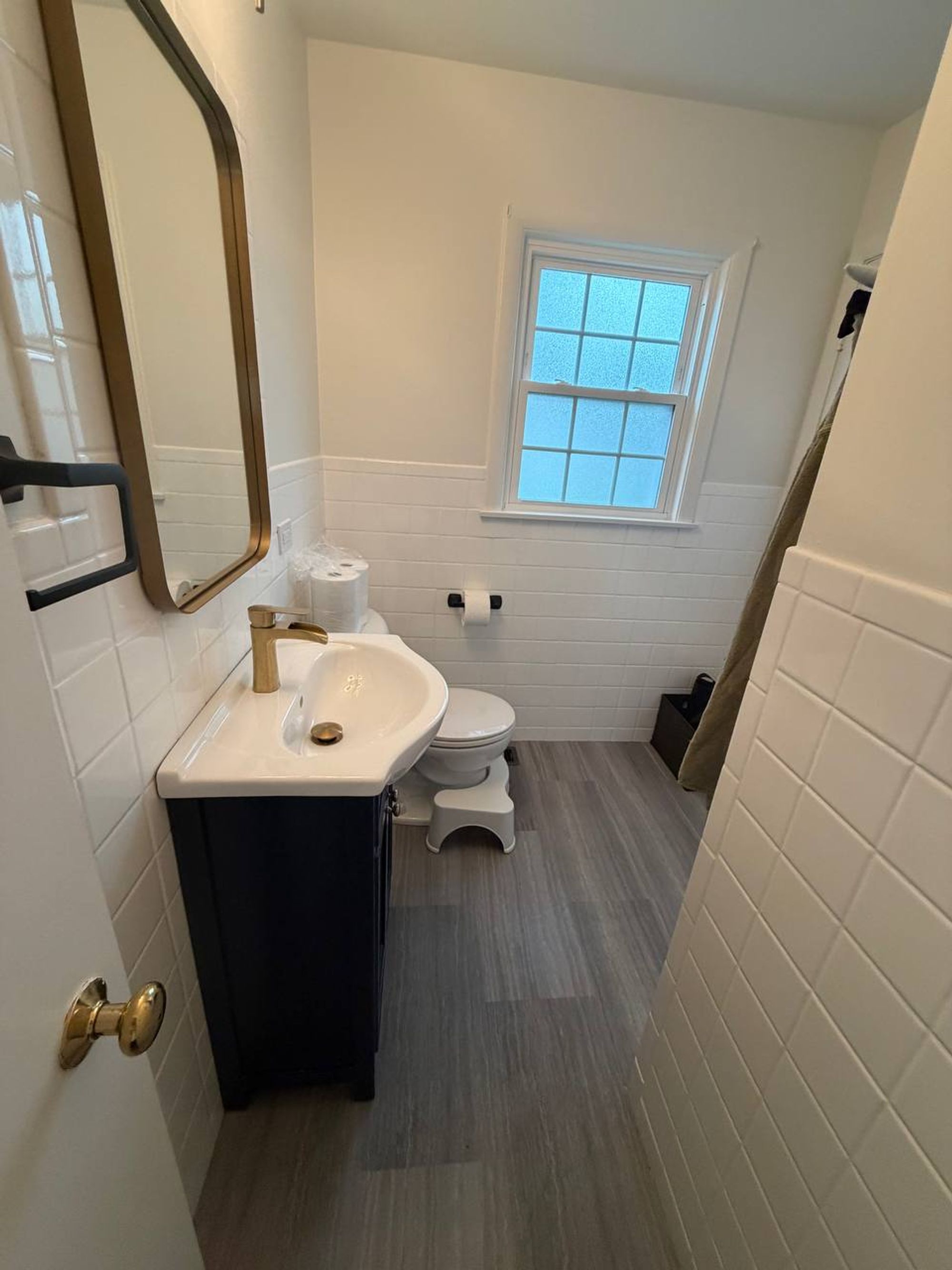 Small bathroom with white tile wainscot and a navy vanity