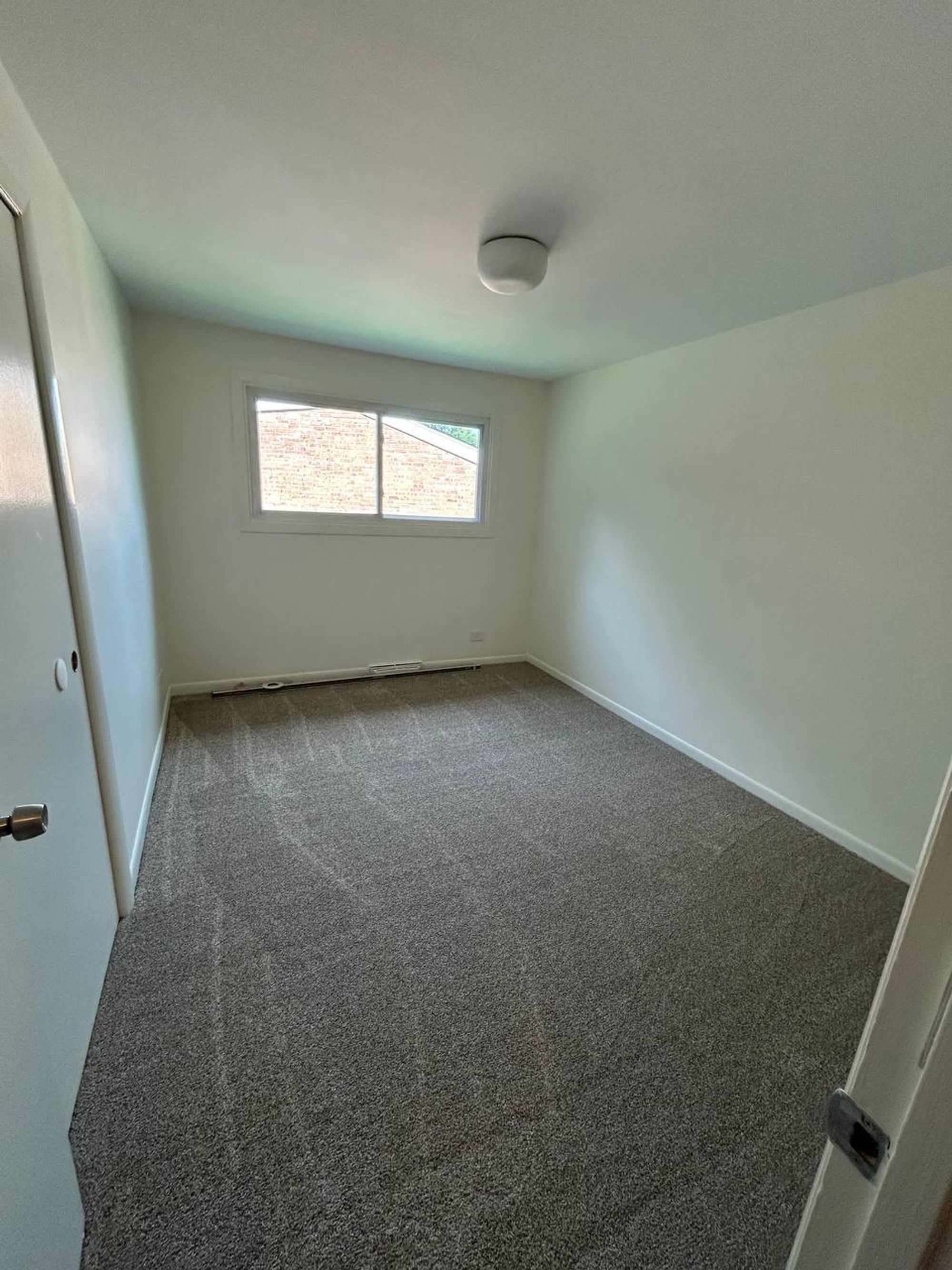 Empty bedroom with gray carpet showing fresh vacuum lines