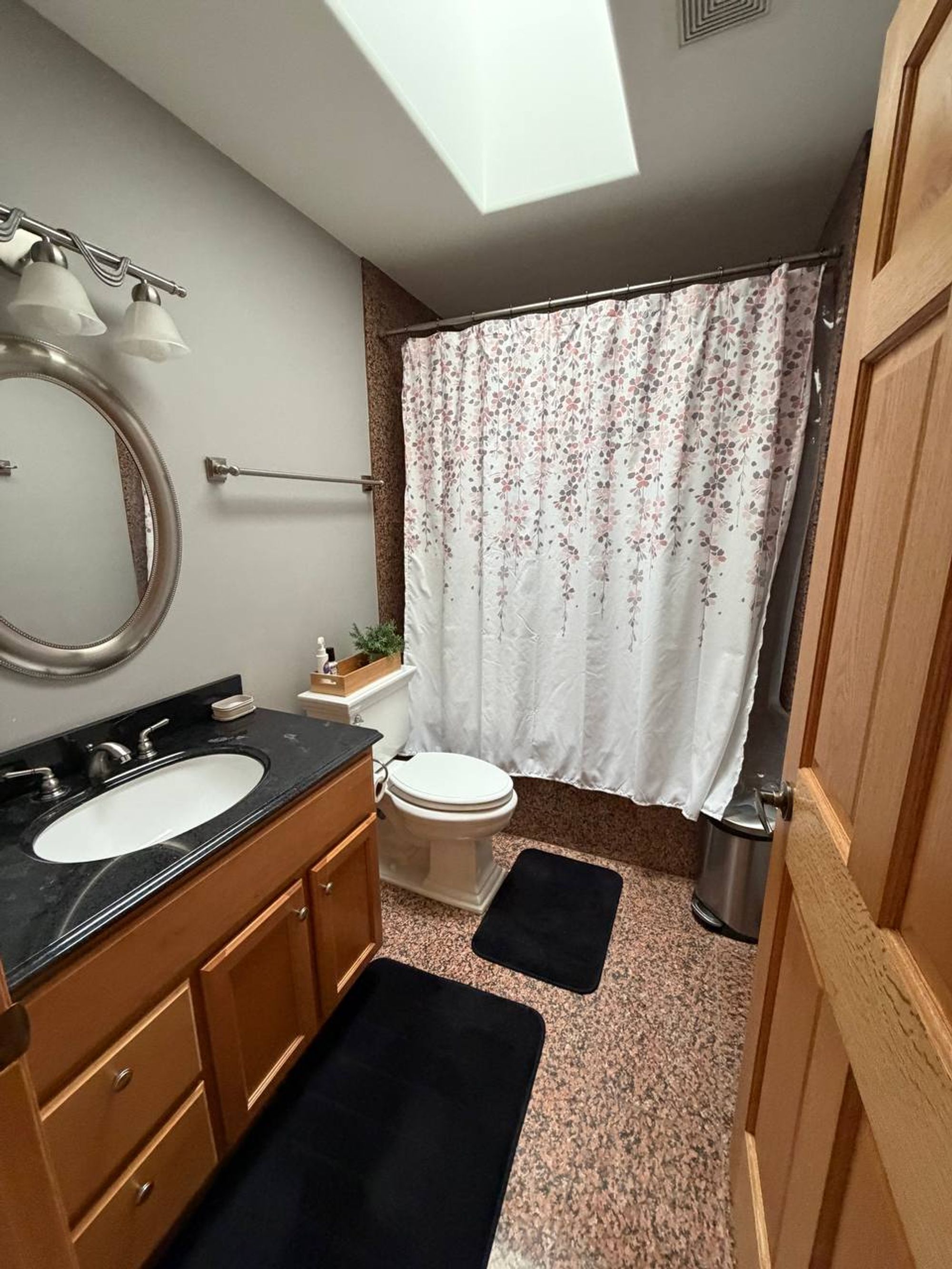 Bathroom with skylight, black counter vanity and floral shower curtain