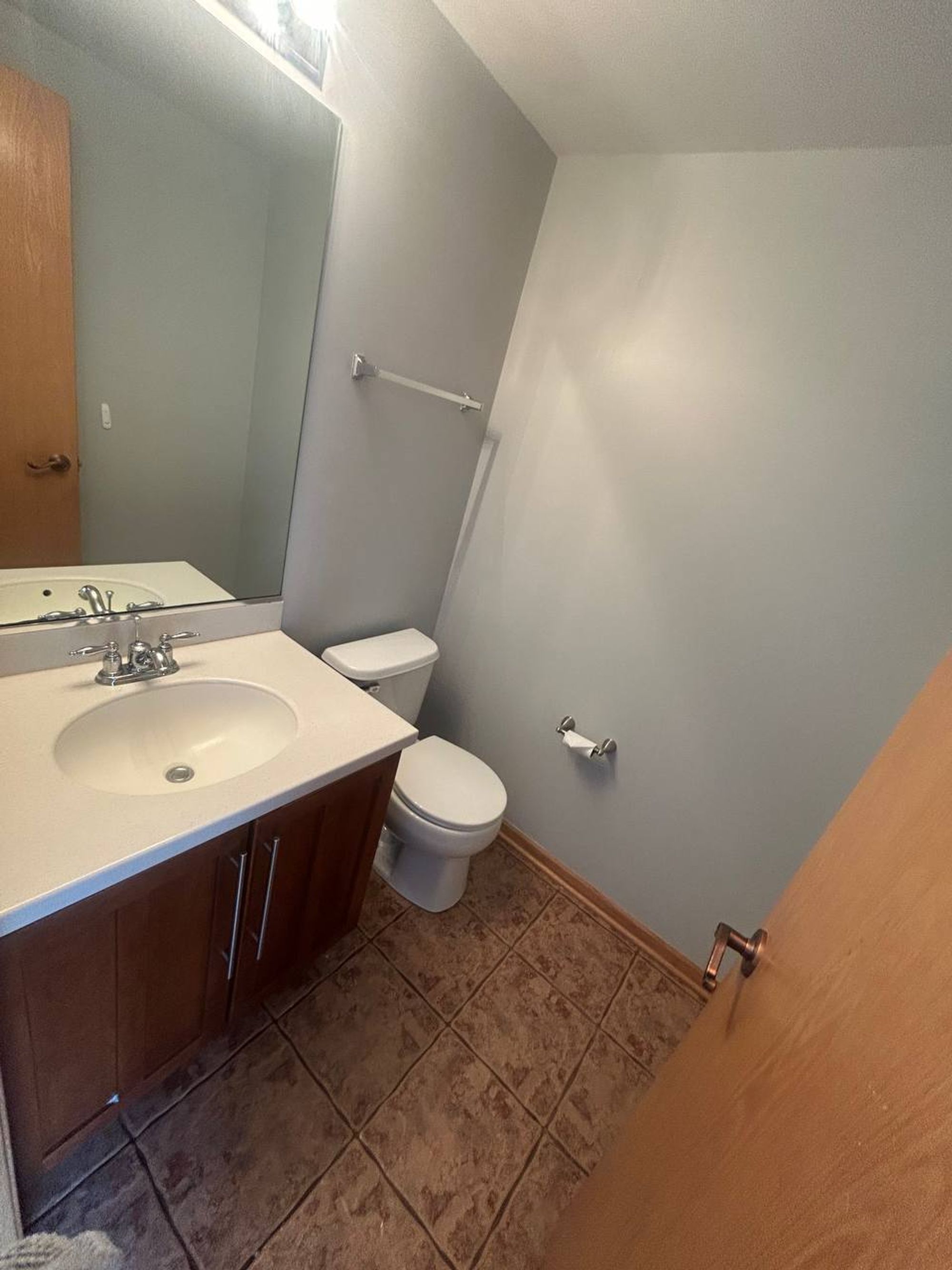 Half bath with wood vanity, mirror and tile floor
