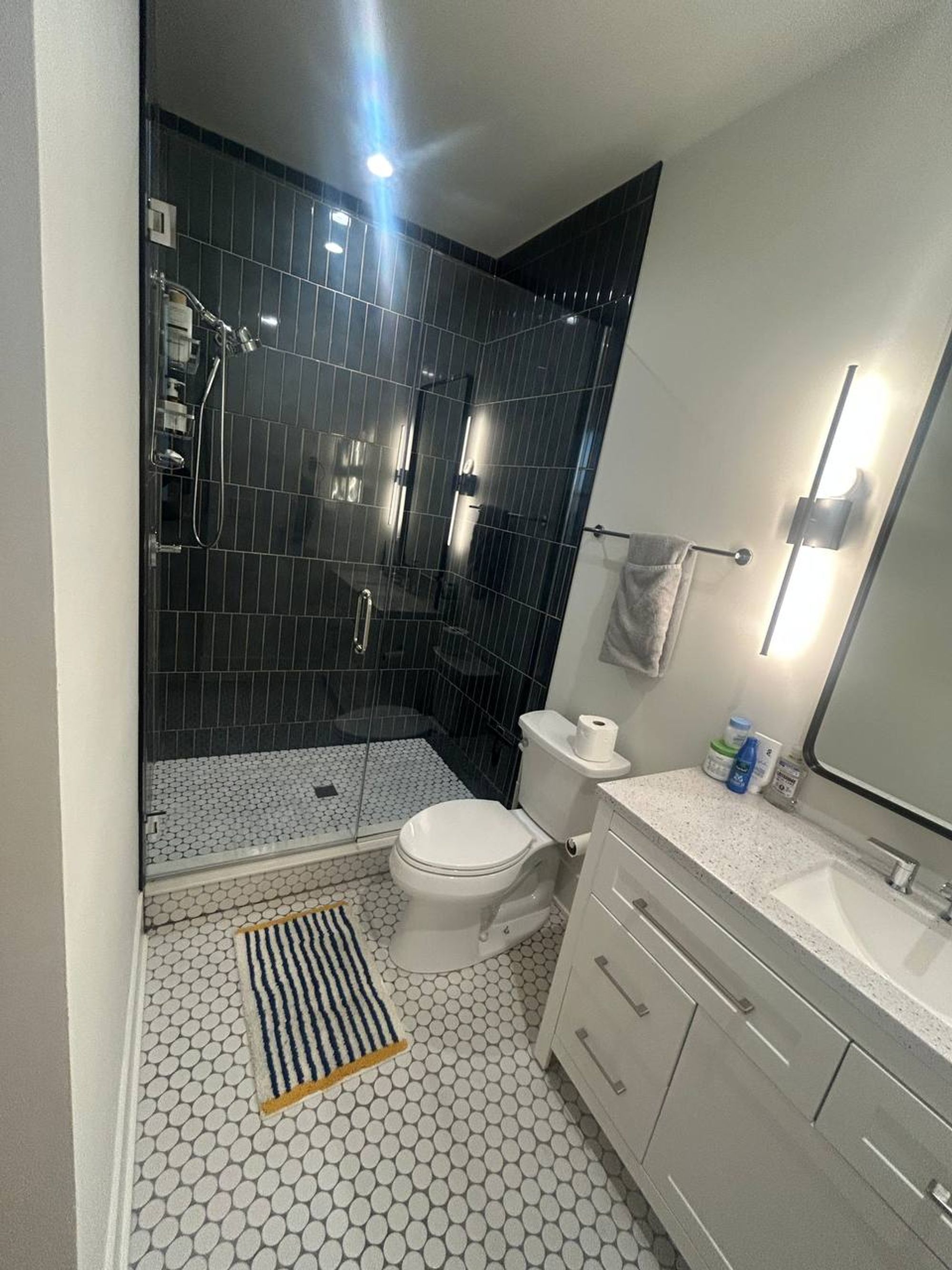 Bathroom with black tile walk-in shower and white hex floor