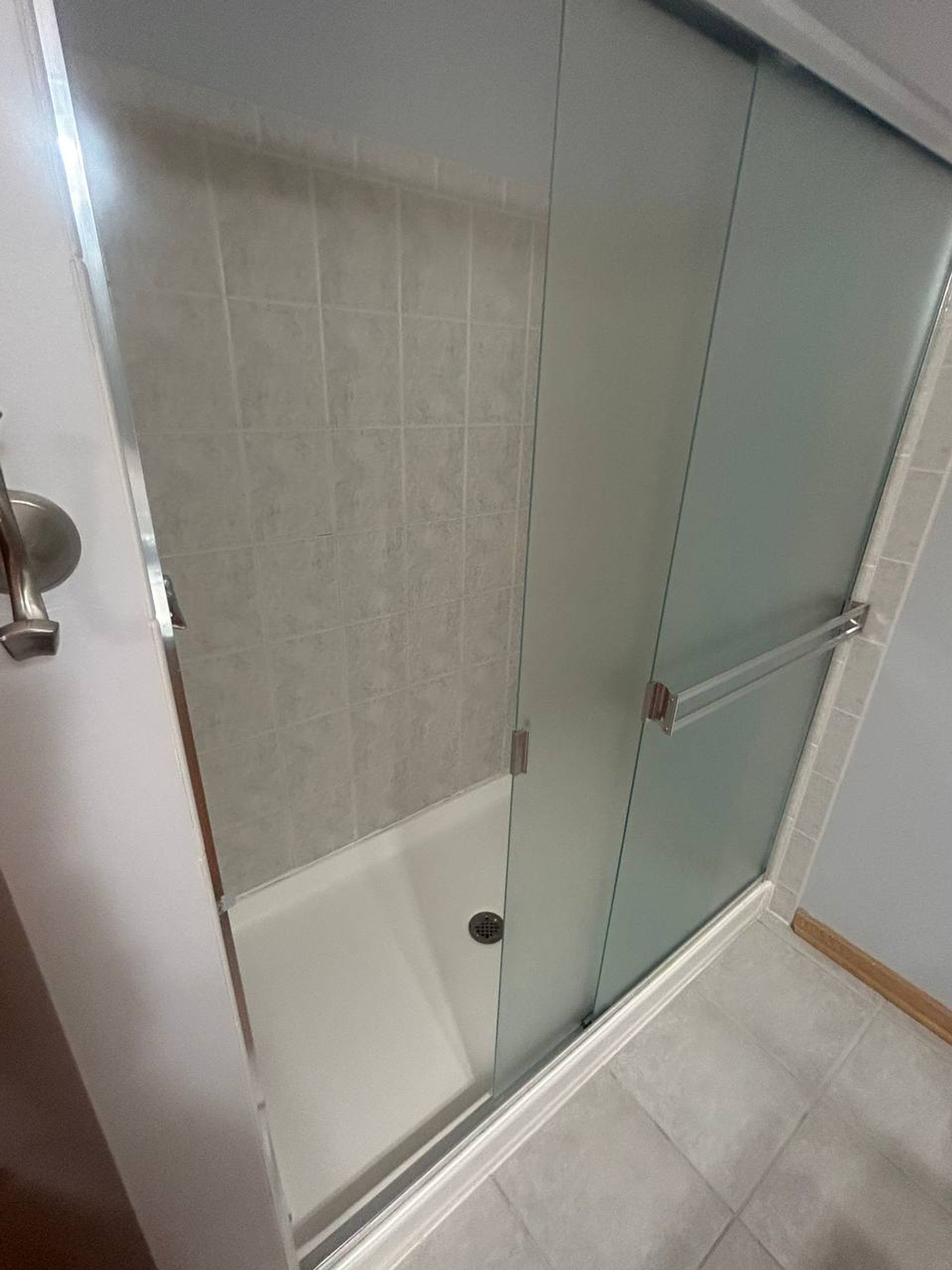 Walk-in shower with frosted sliding glass doors and clean white base