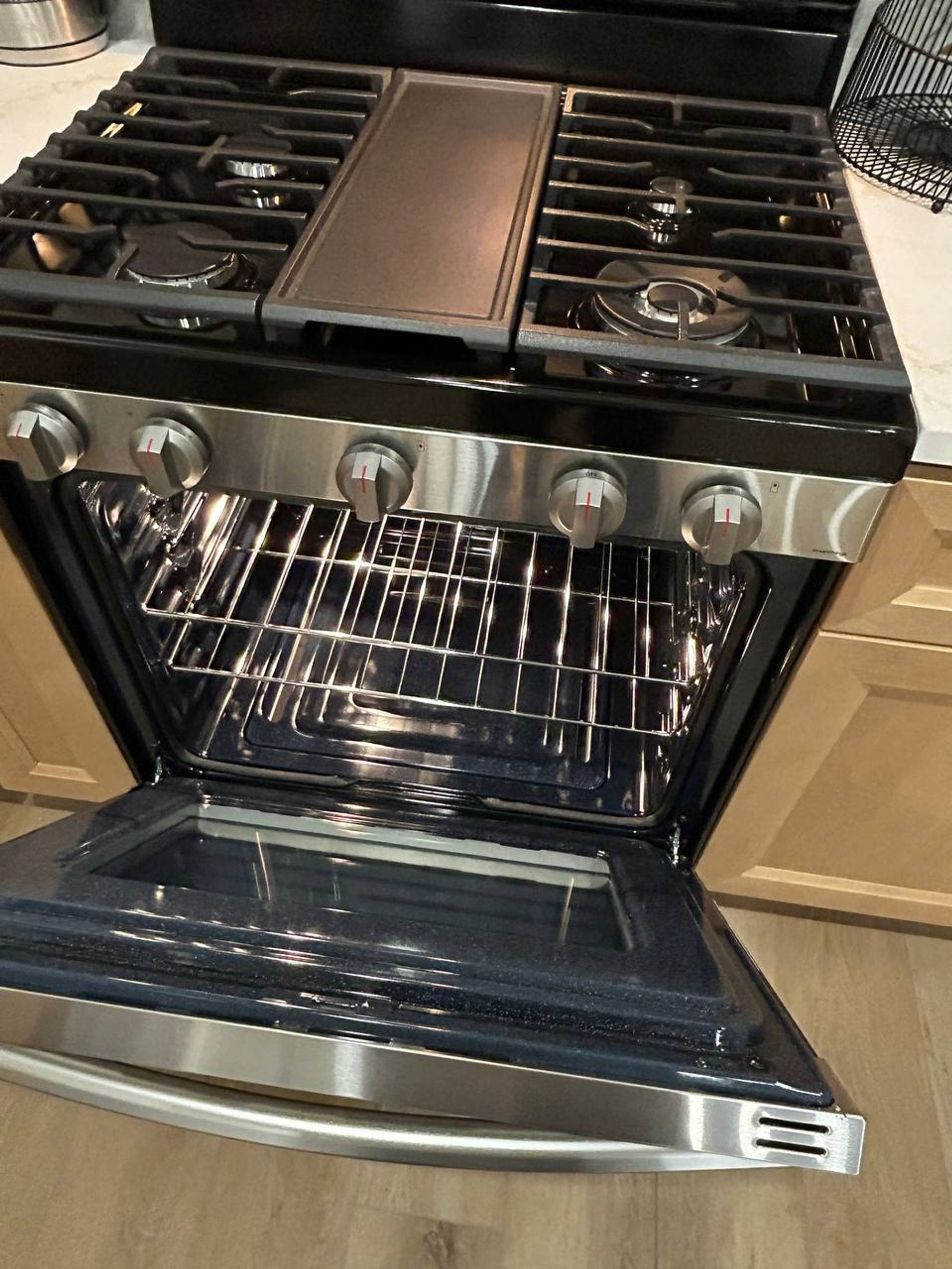 Open oven with clean racks under a five burner gas cooktop