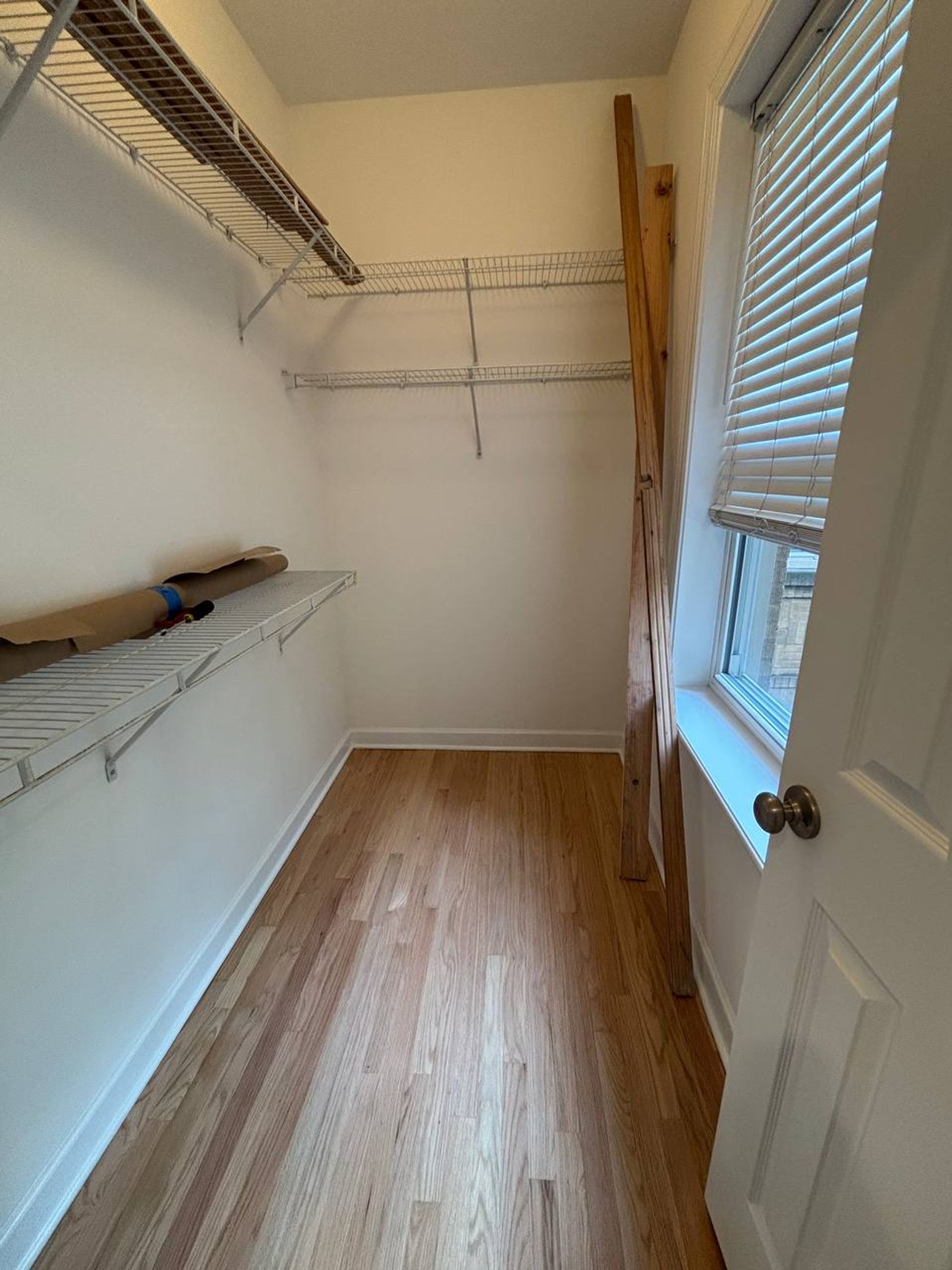 Empty walk-in closet with wire shelves and light wood floor