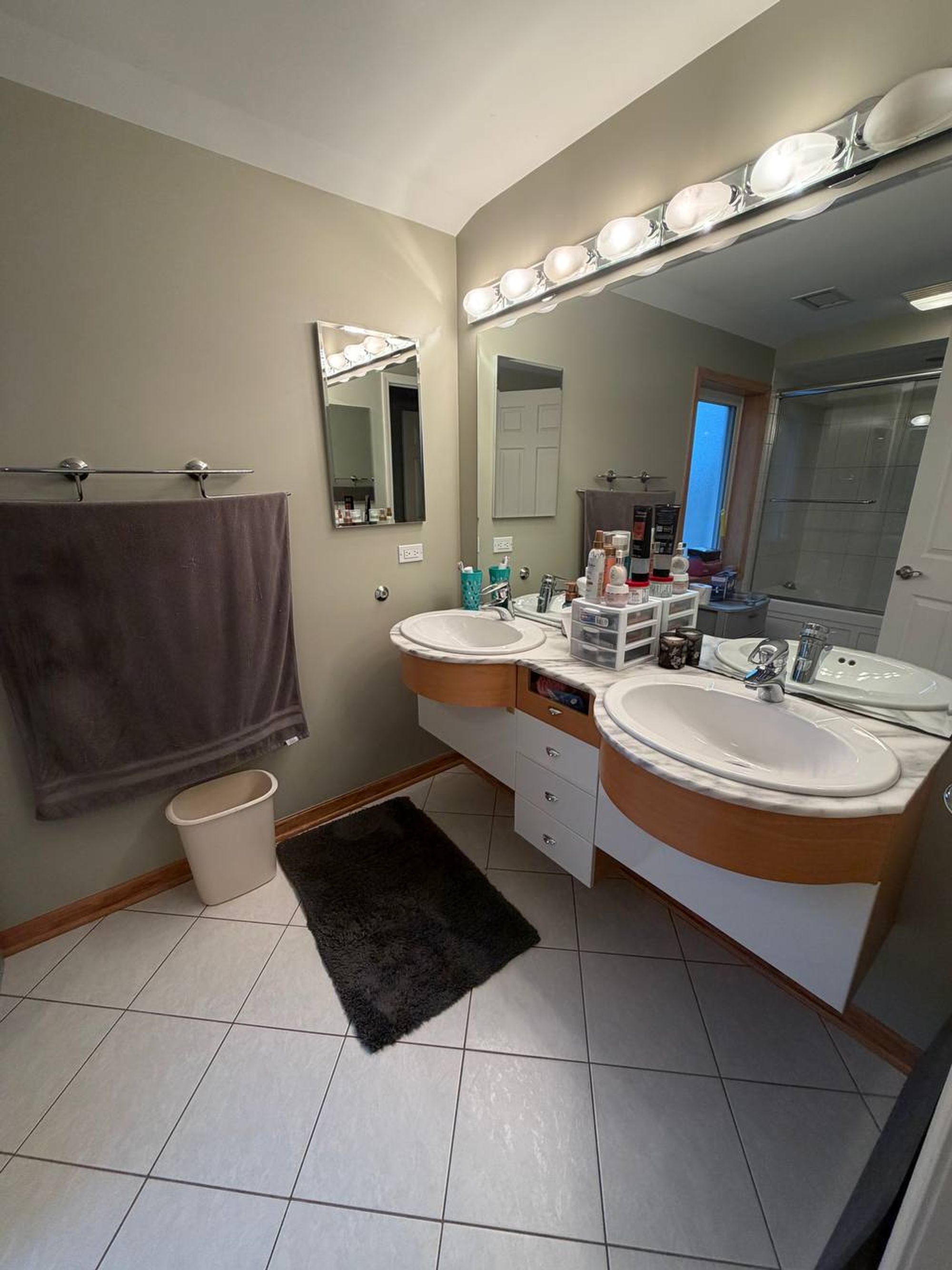 Bathroom with double sink vanity, wide mirror and white tile floor