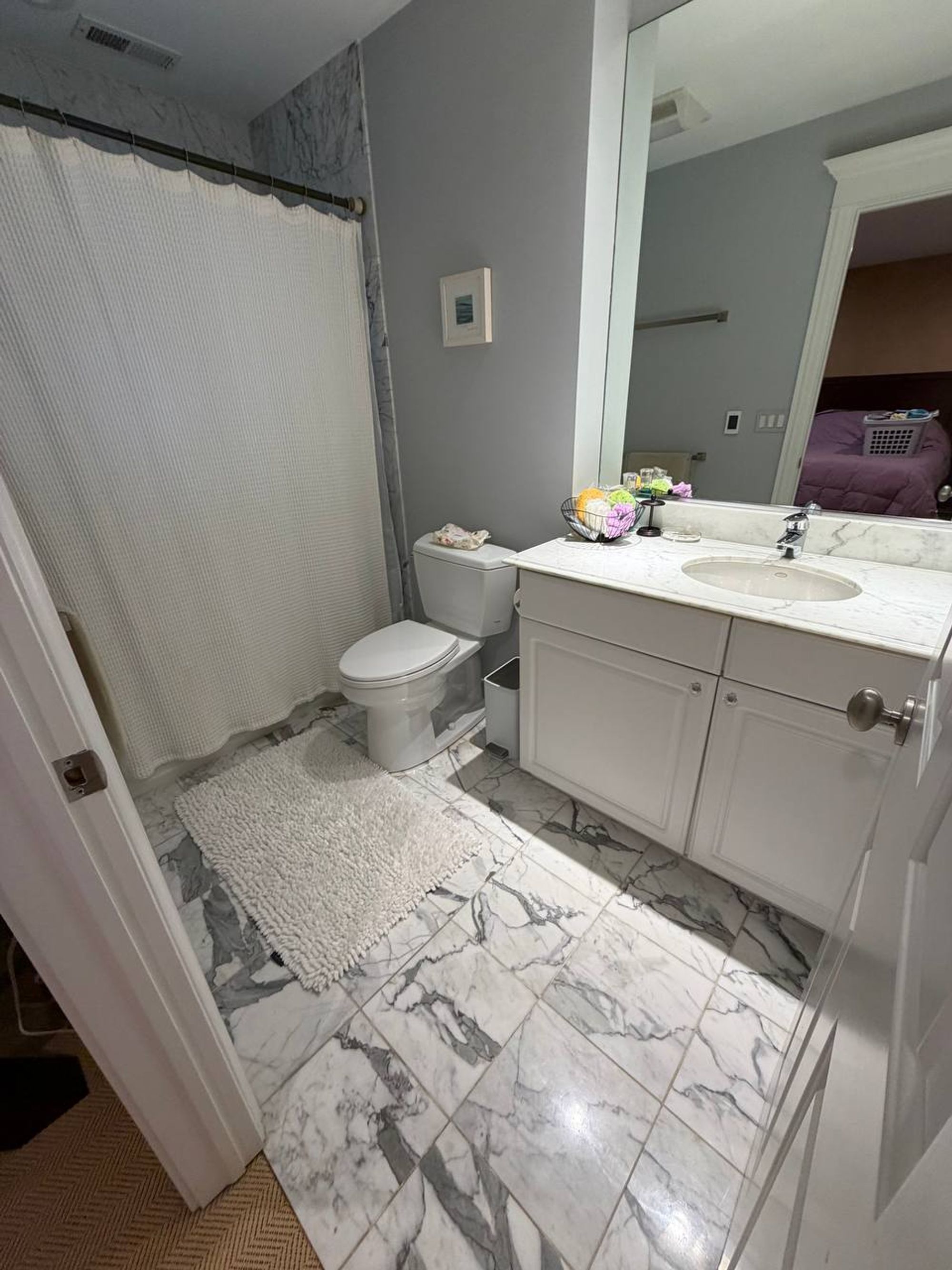 Bathroom with white vanity, marble tile floor and clean wide mirror