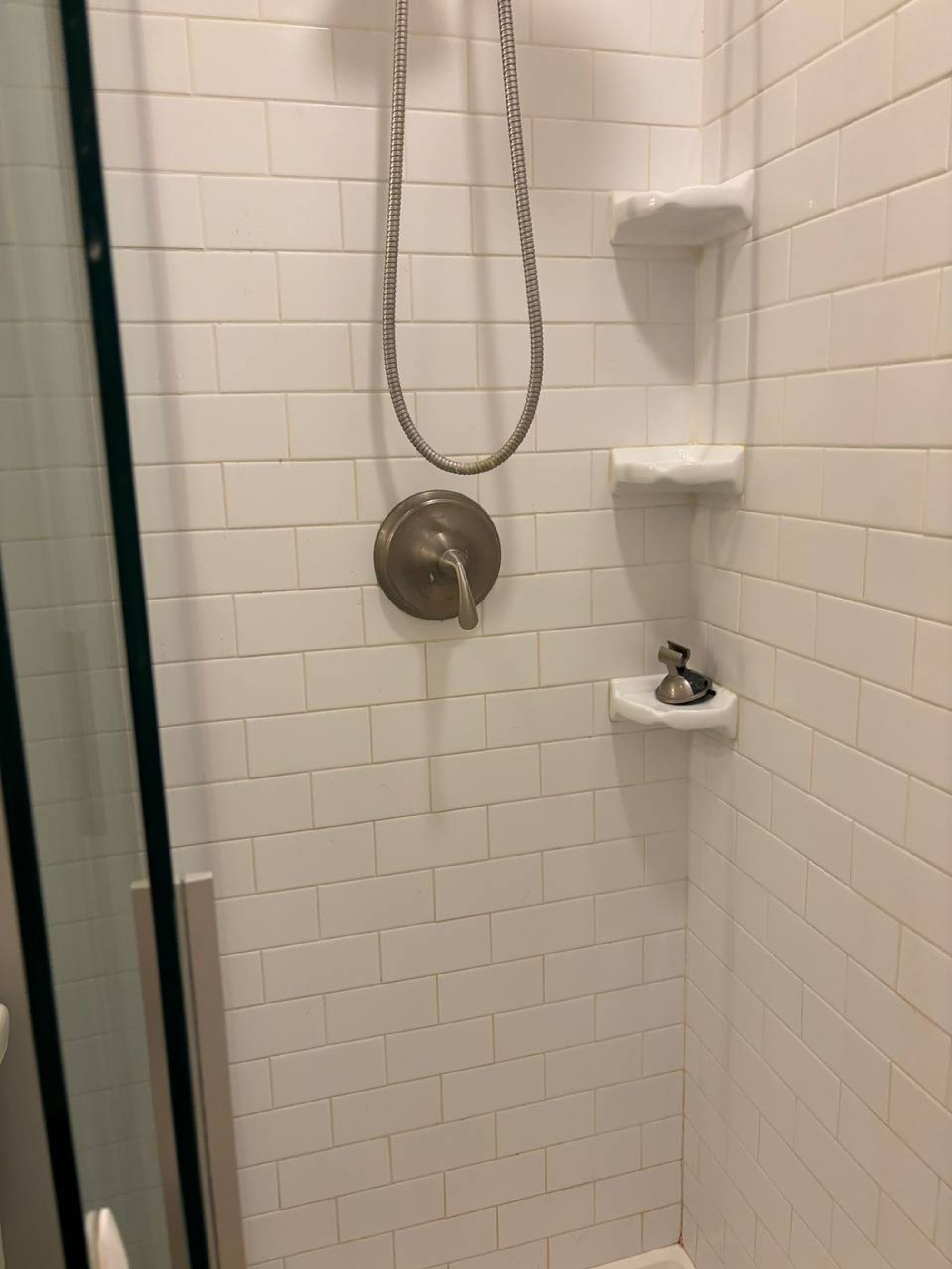 White subway tile shower with corner shelves and brushed nickel valve