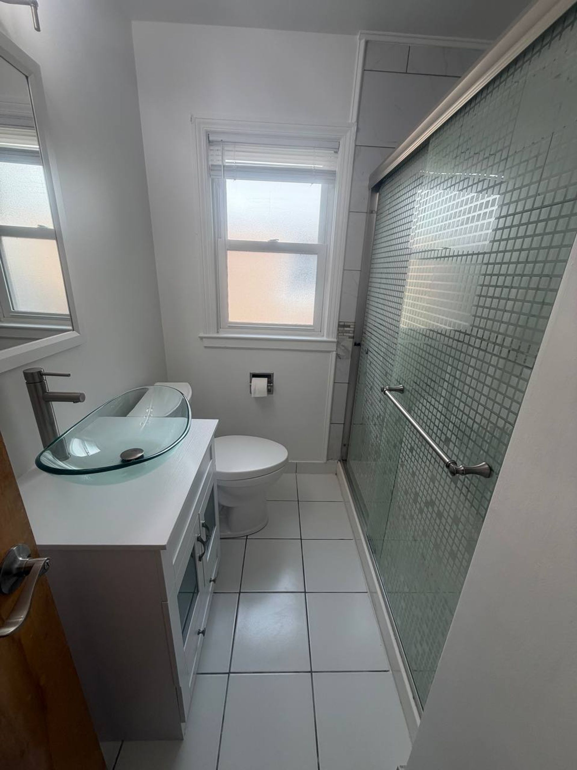 Bathroom with glass bowl sink, white tile floor and sliding shower door