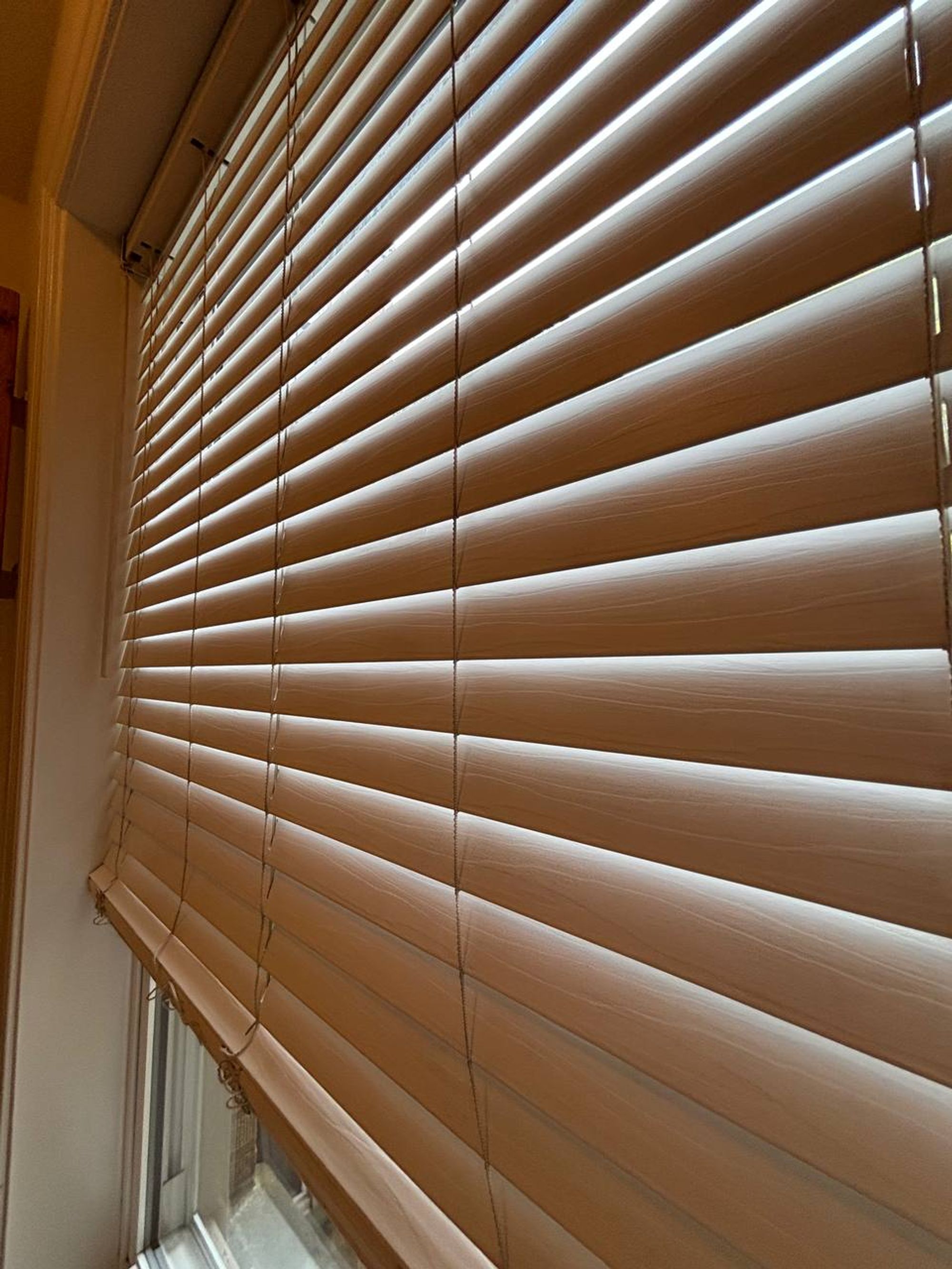 Wood blinds dusted slat by slat on a bedroom window