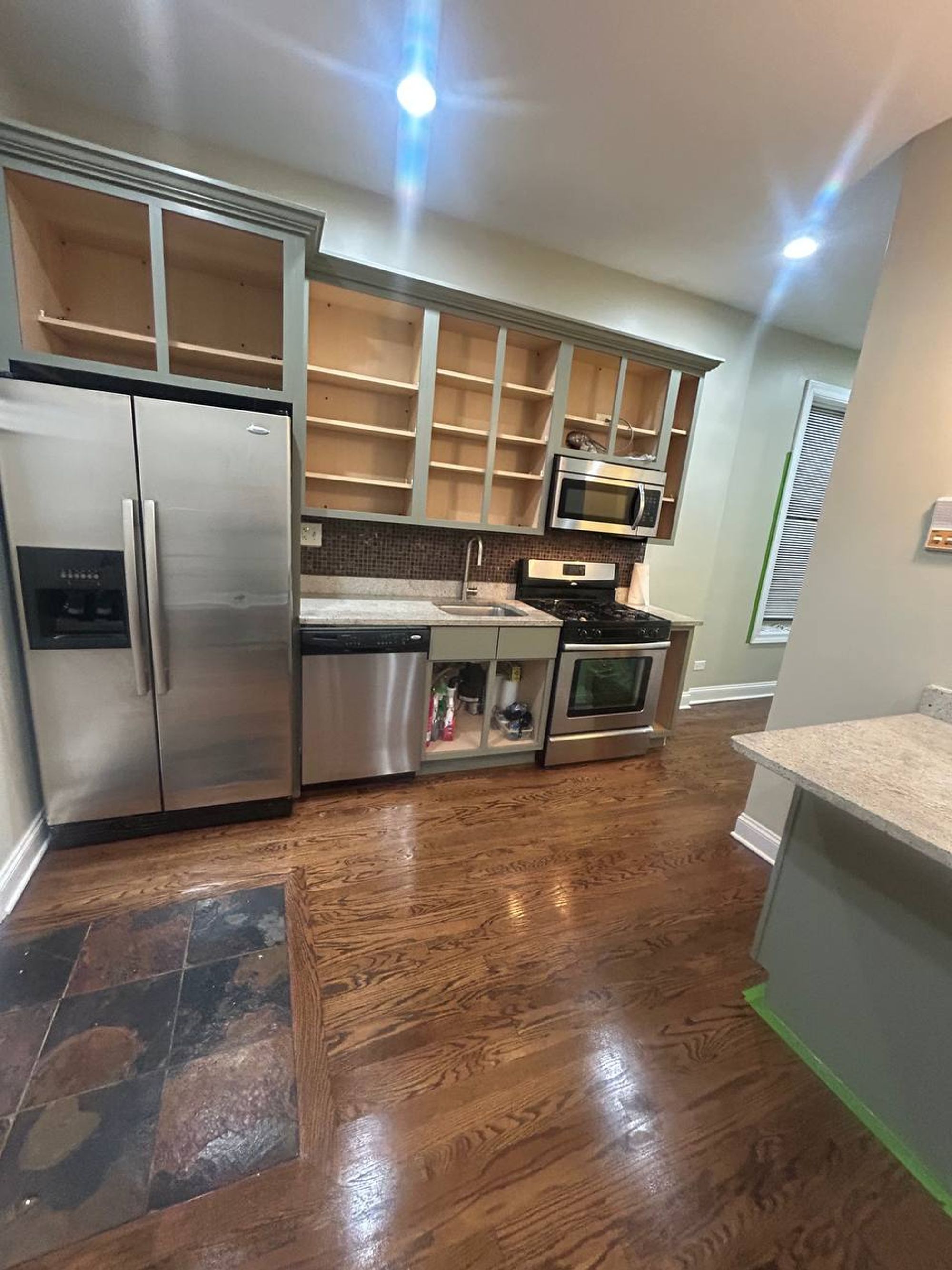Long kitchen with stainless fridge, open shelves and dark wood floor