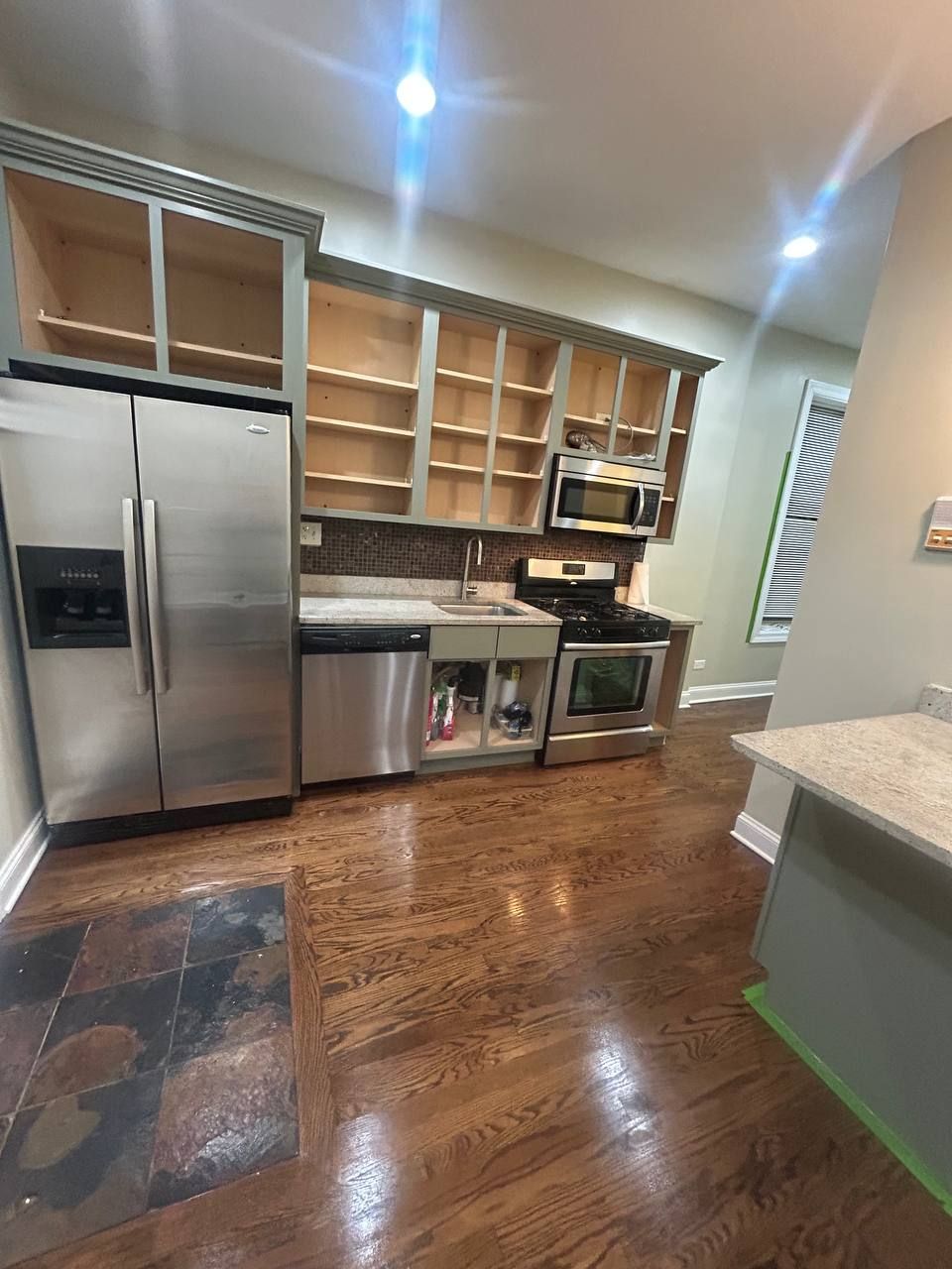 Long kitchen with stainless fridge, open shelves and dark wood floor