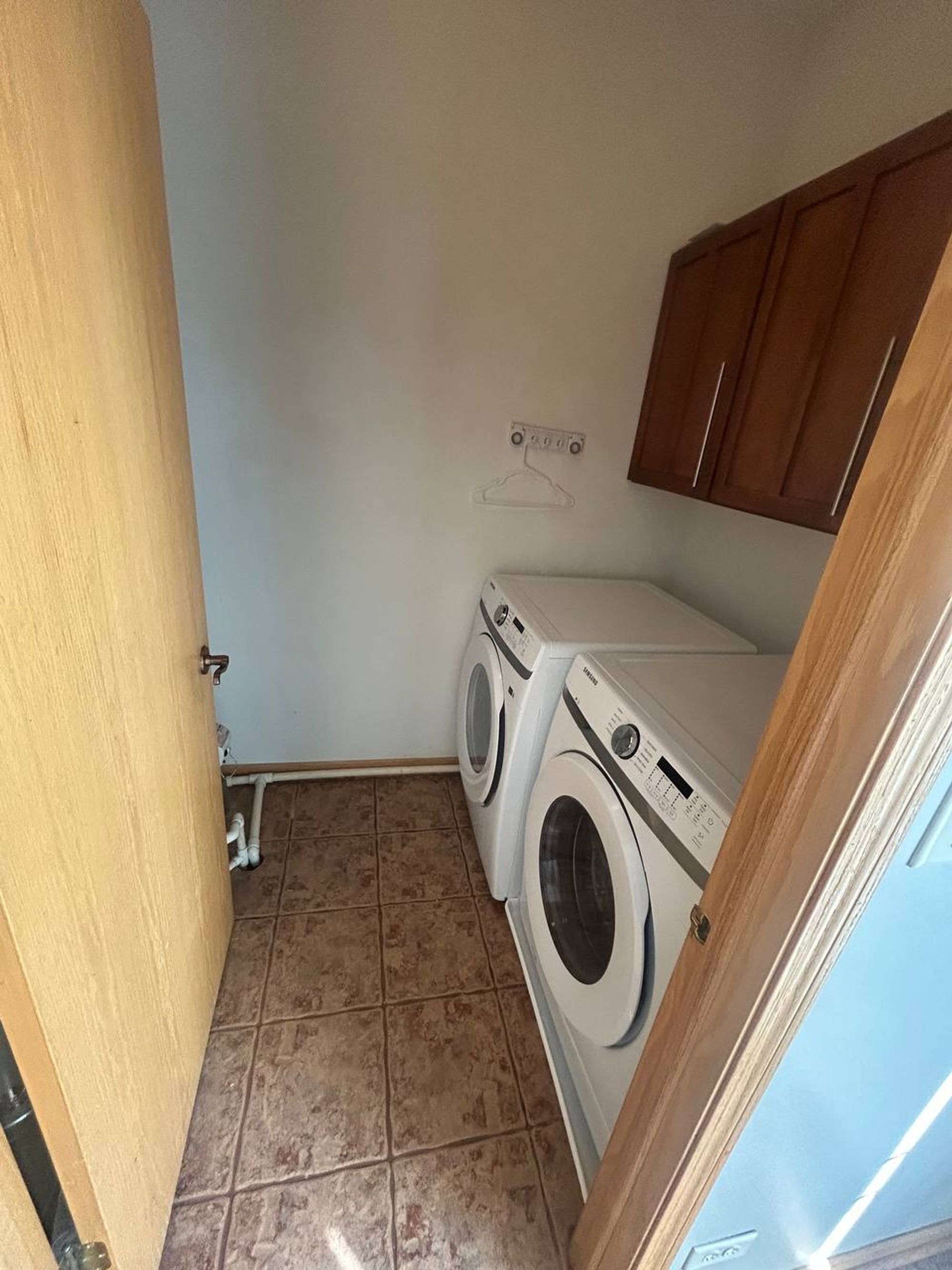 Laundry room with front-load washer and dryer and wood cabinets