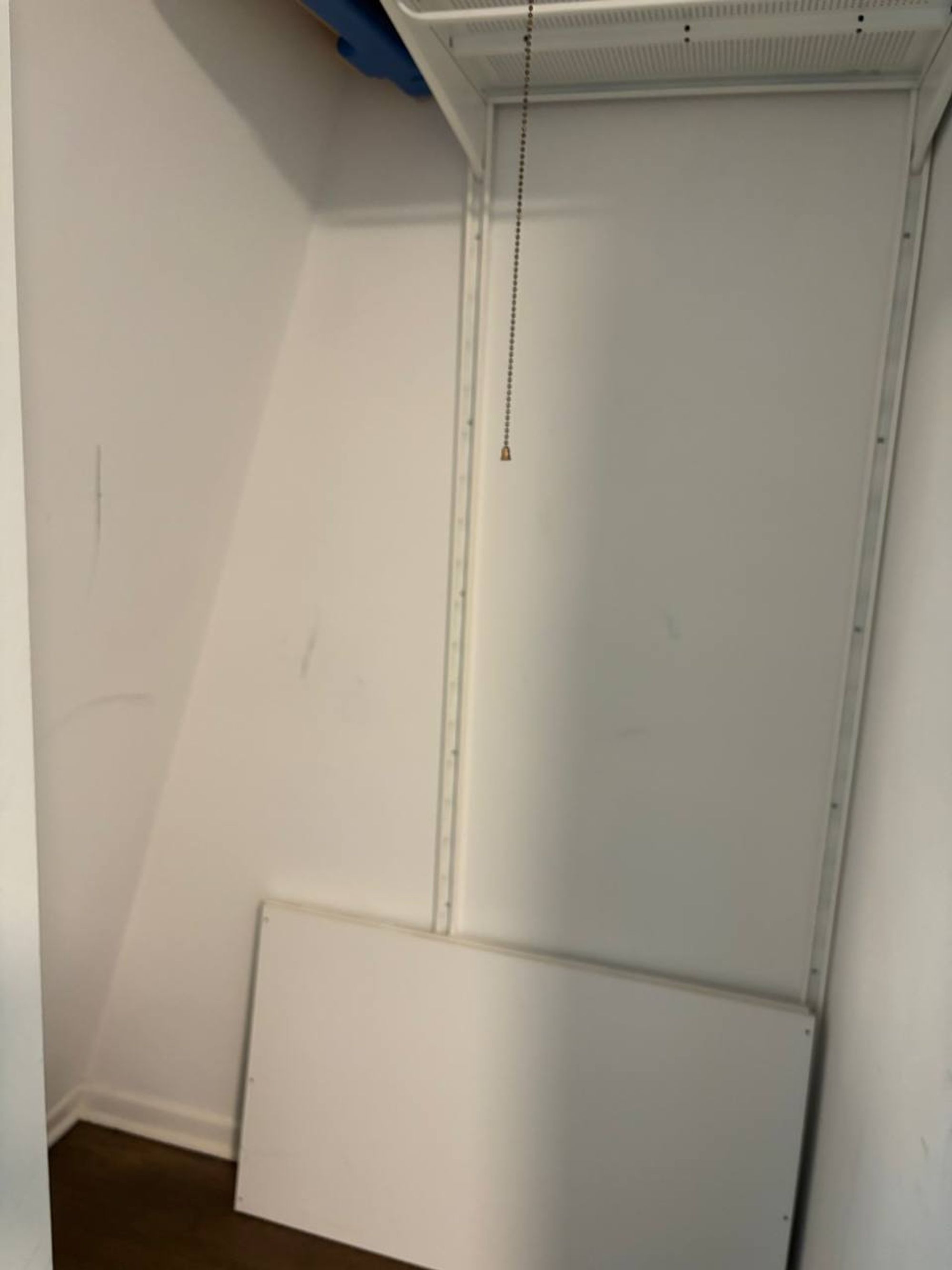 Empty closet with white walls and wire shelf above