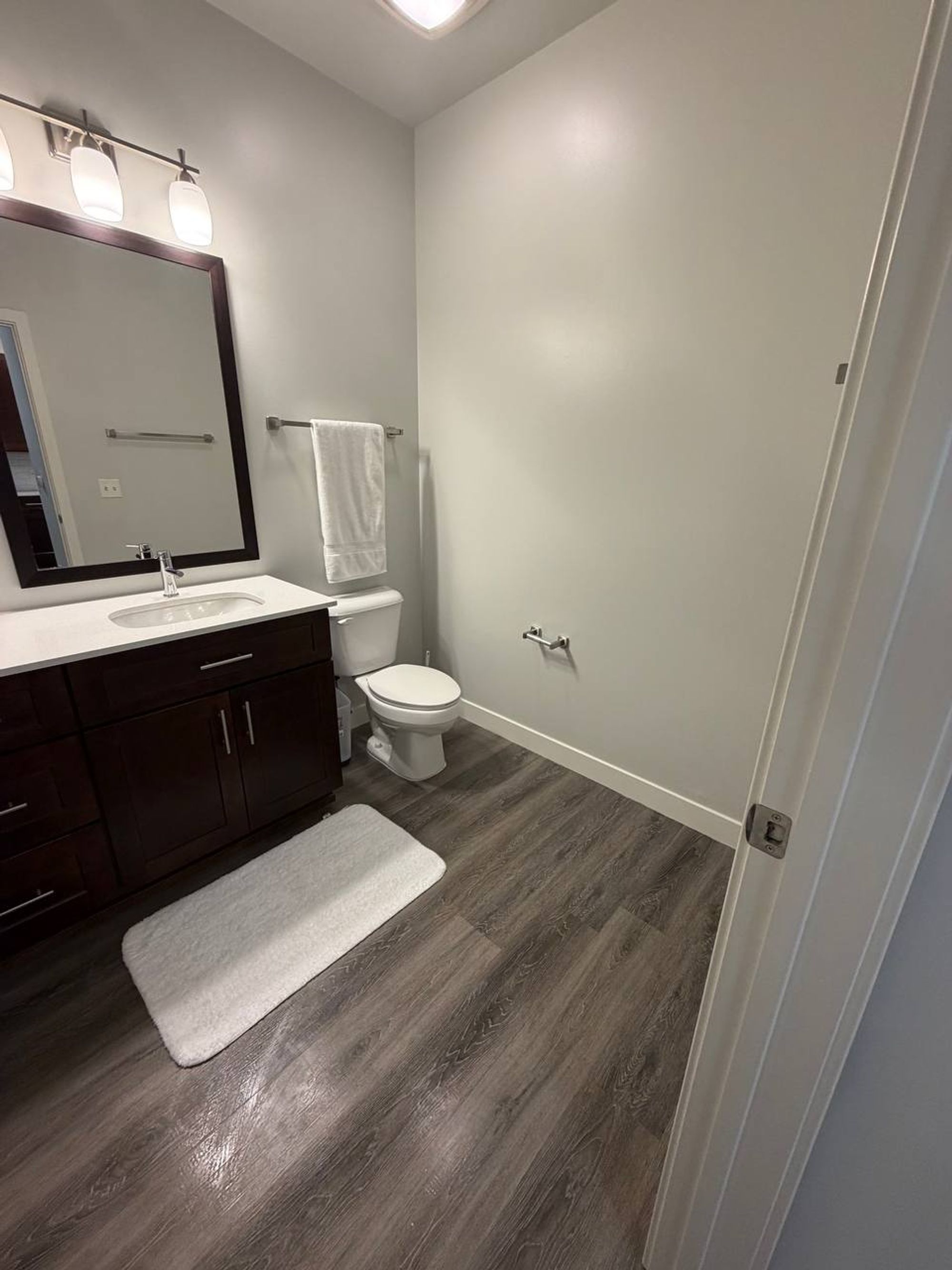 Half bath with dark vanity, hanging towel and wood-look floor