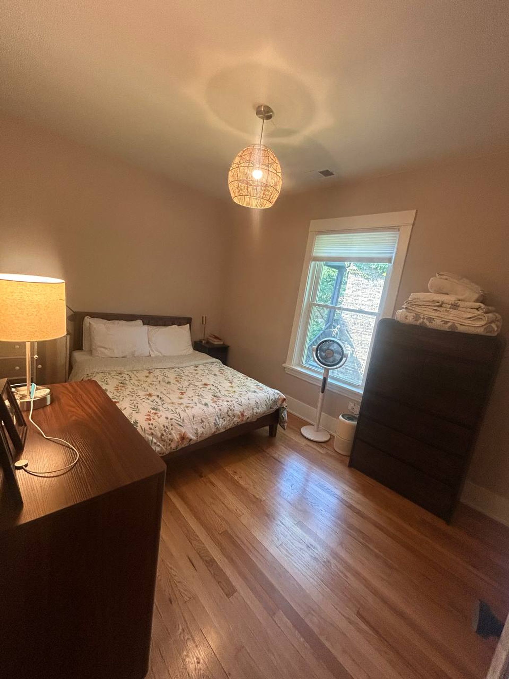 Bedroom with floral bedding, wood dresser and hardwood floor