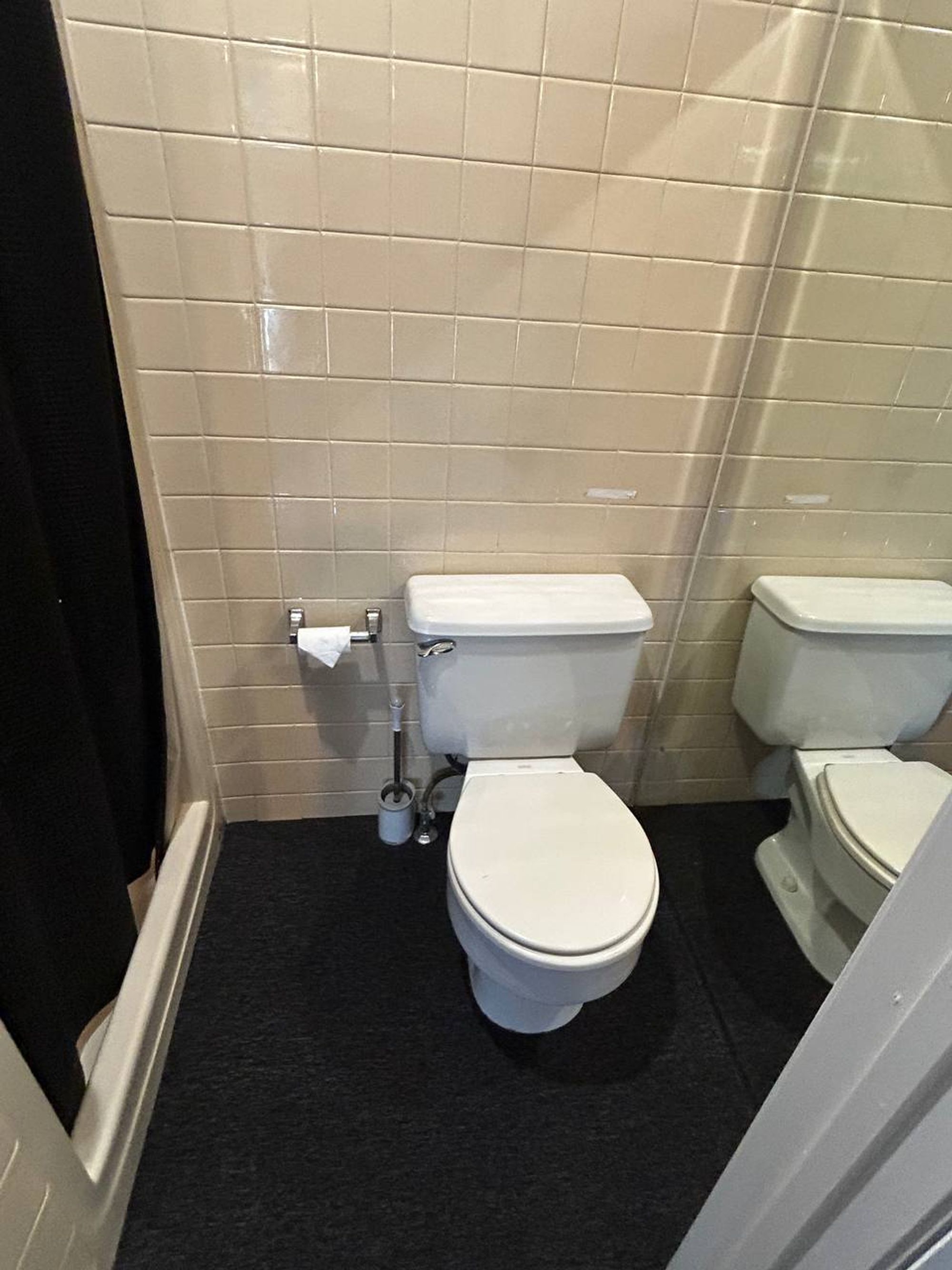 Clean bathroom with white toilet against beige wall tile