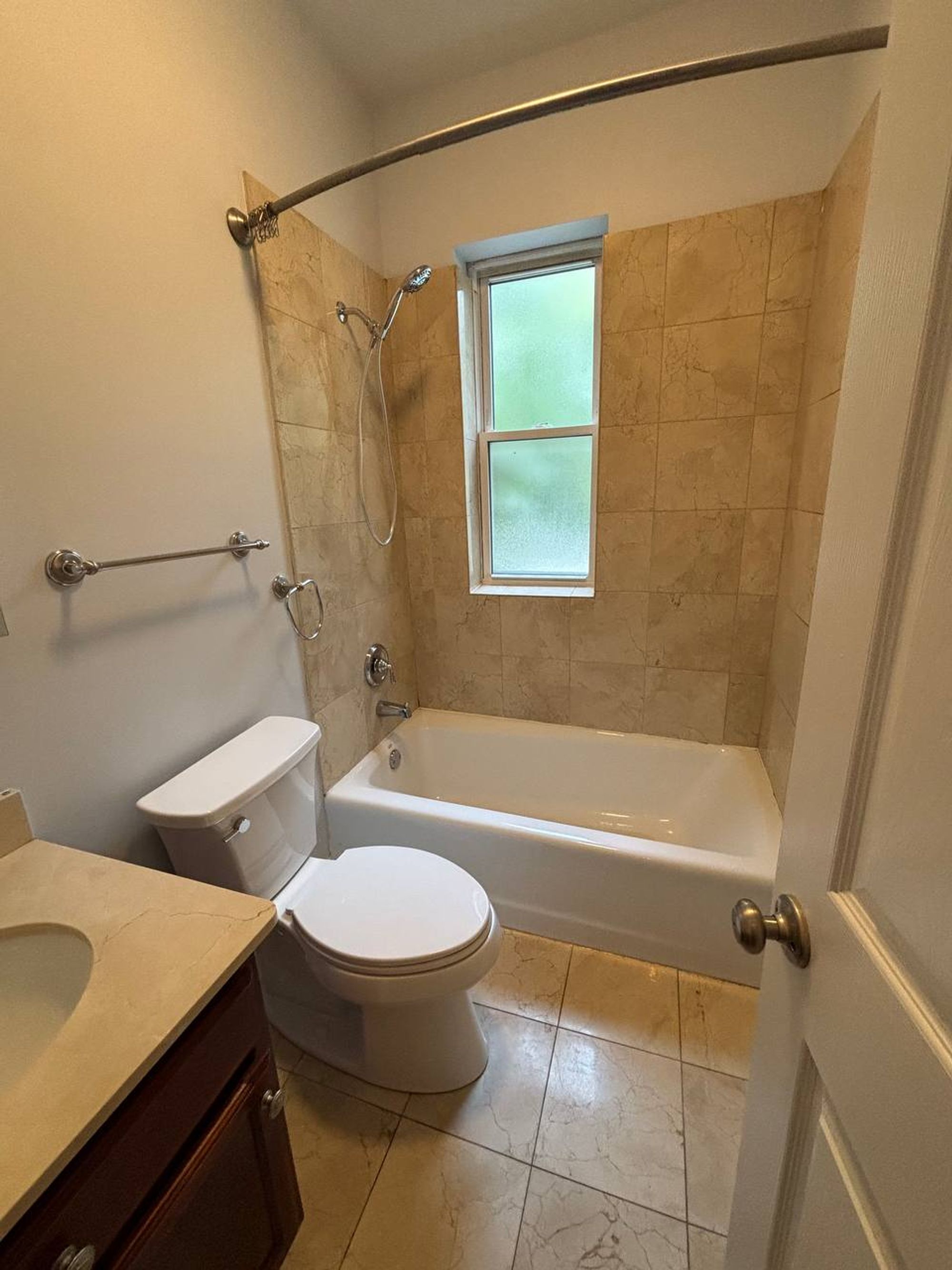 Second bathroom with white tub, tile surround and dark vanity