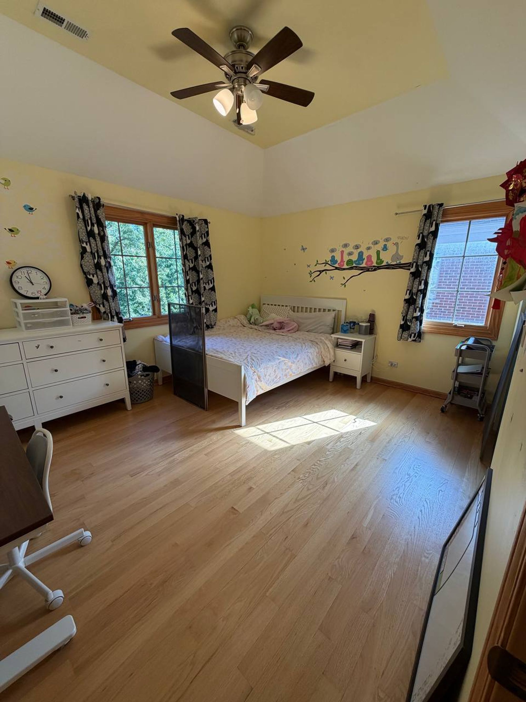 Bright bedroom with yellow walls, wall decals and light hardwood floor