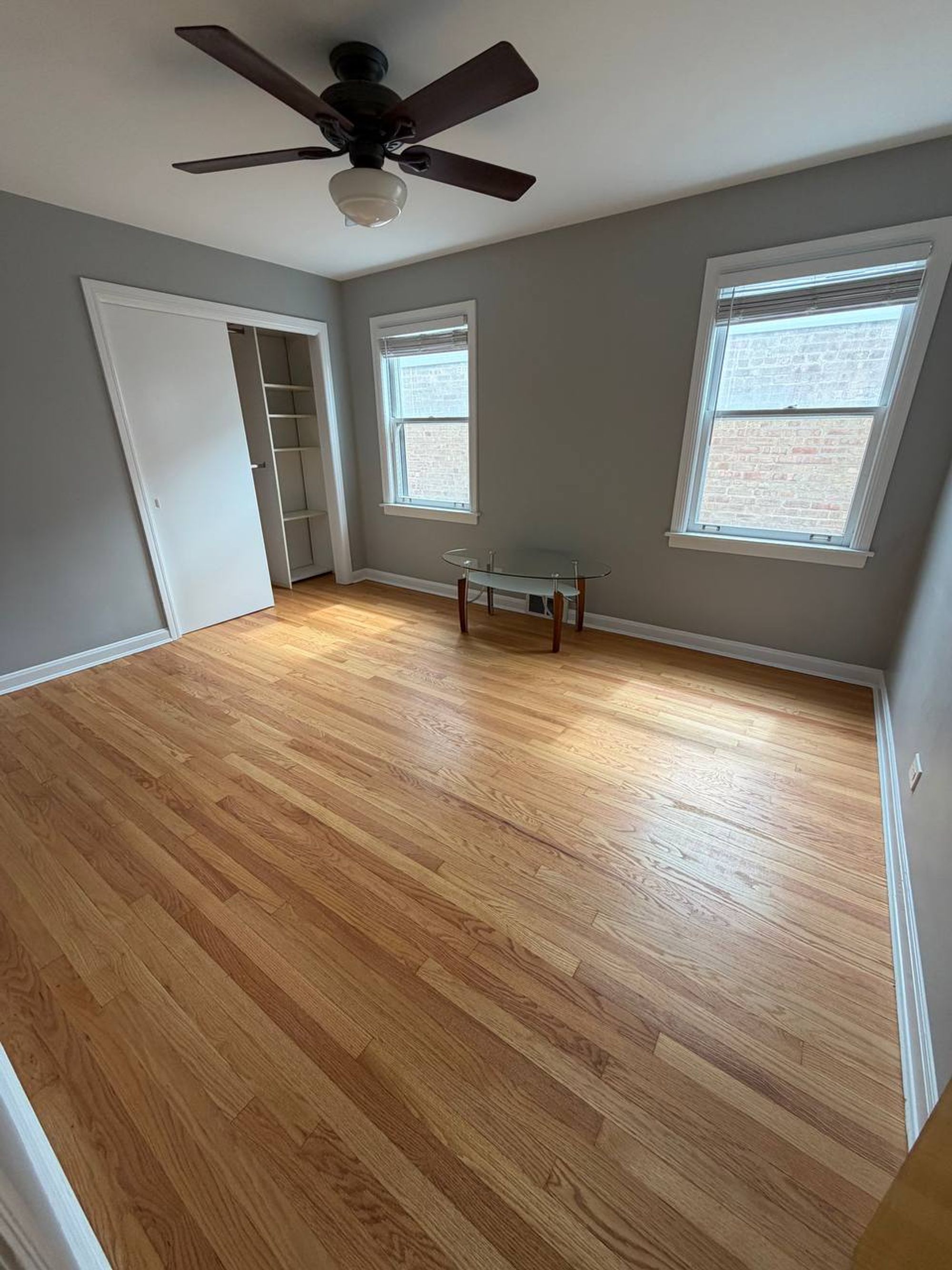 Bedroom with glass side table, open closet and light oak floor