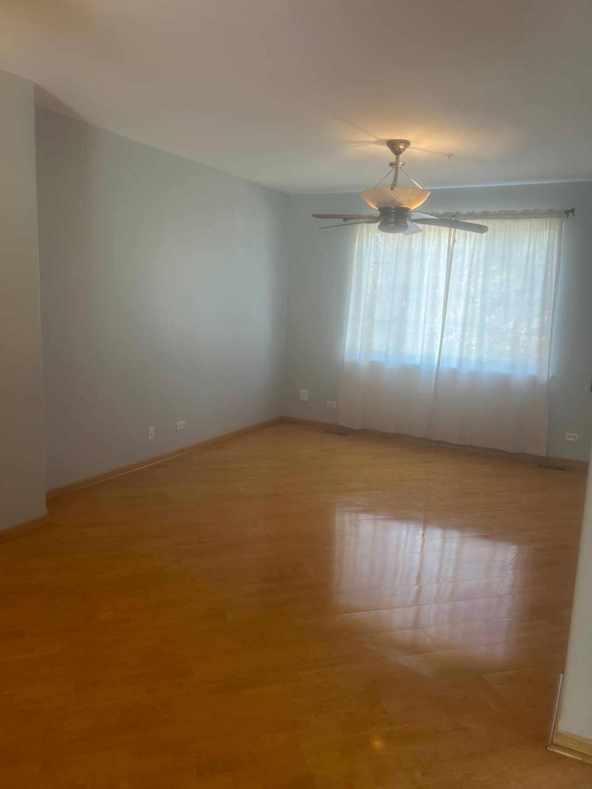 Empty living room with sheer curtains and polished wood floor