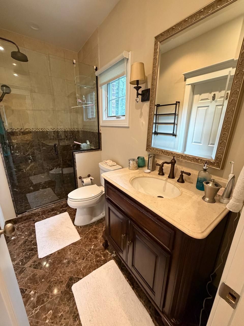 Bathroom with glass shower, brown marble floor and cream stone vanity