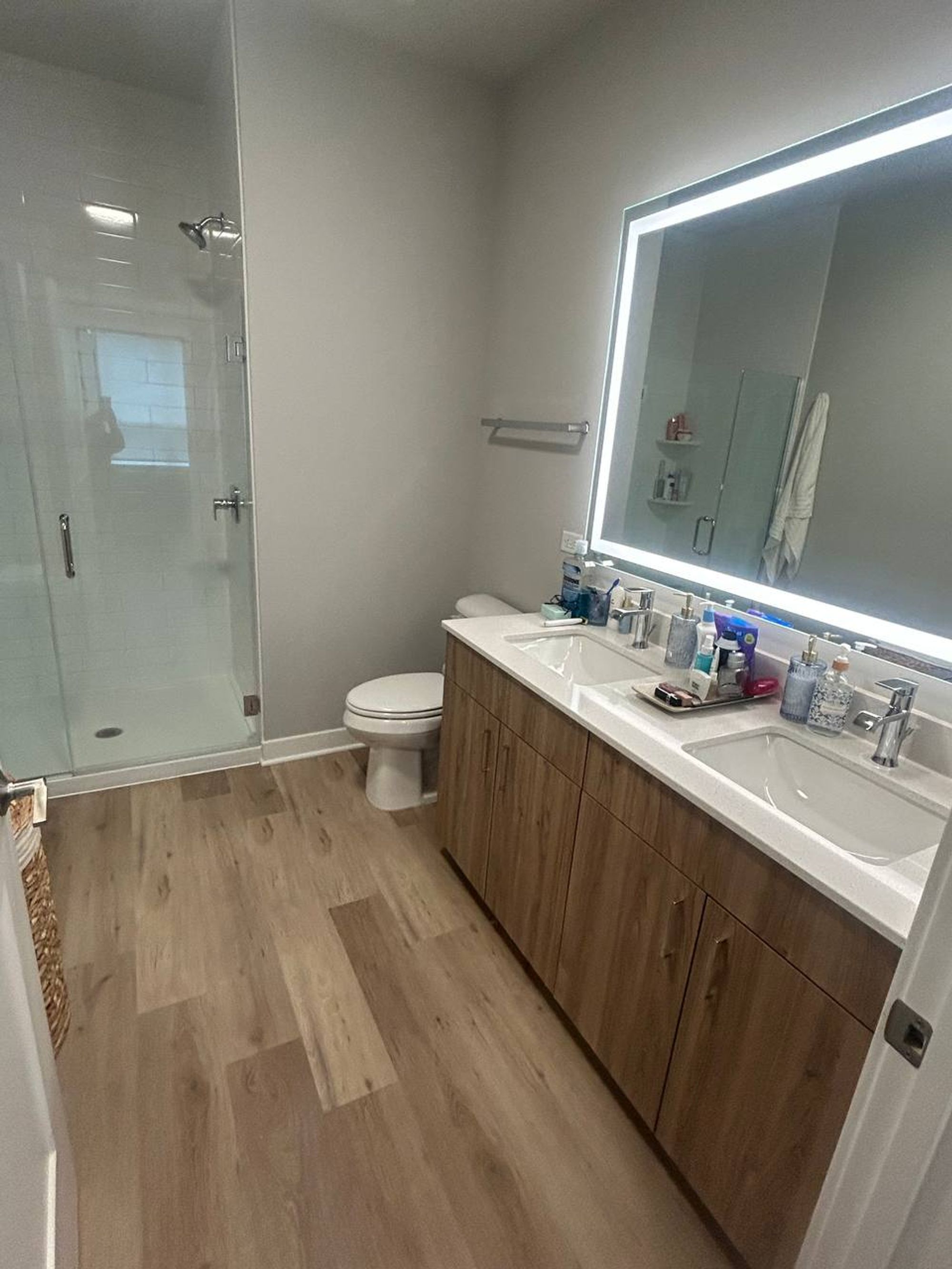 Bathroom with double sink vanity, lit mirror and glass shower